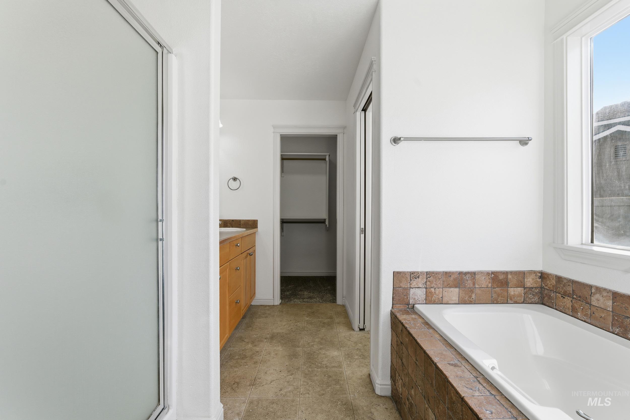 Bathroom featuring vanity, a spacious closet, a bath, and a stall shower
