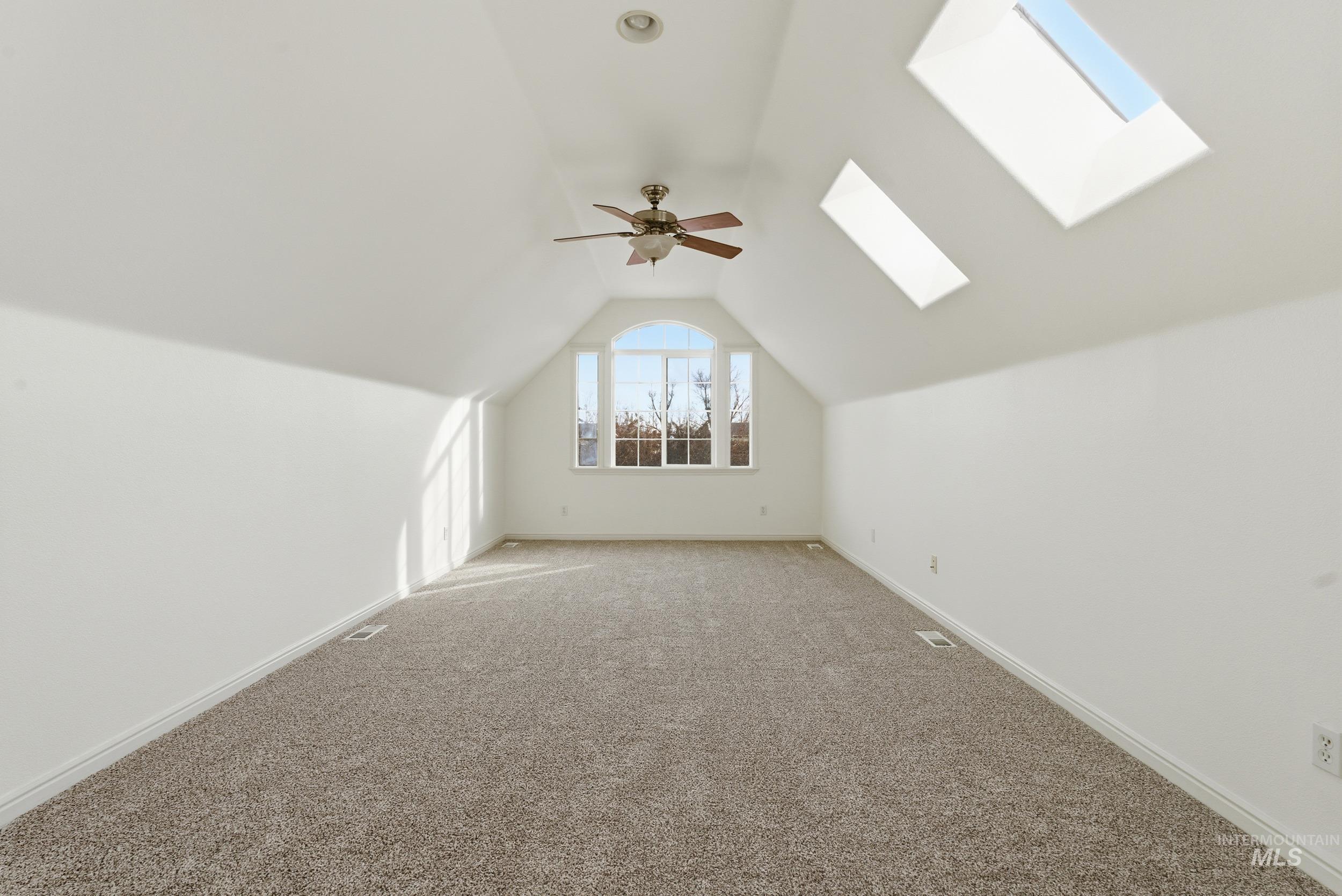 Additional living space with lofted ceiling, a skylight, carpet, and ceiling fan