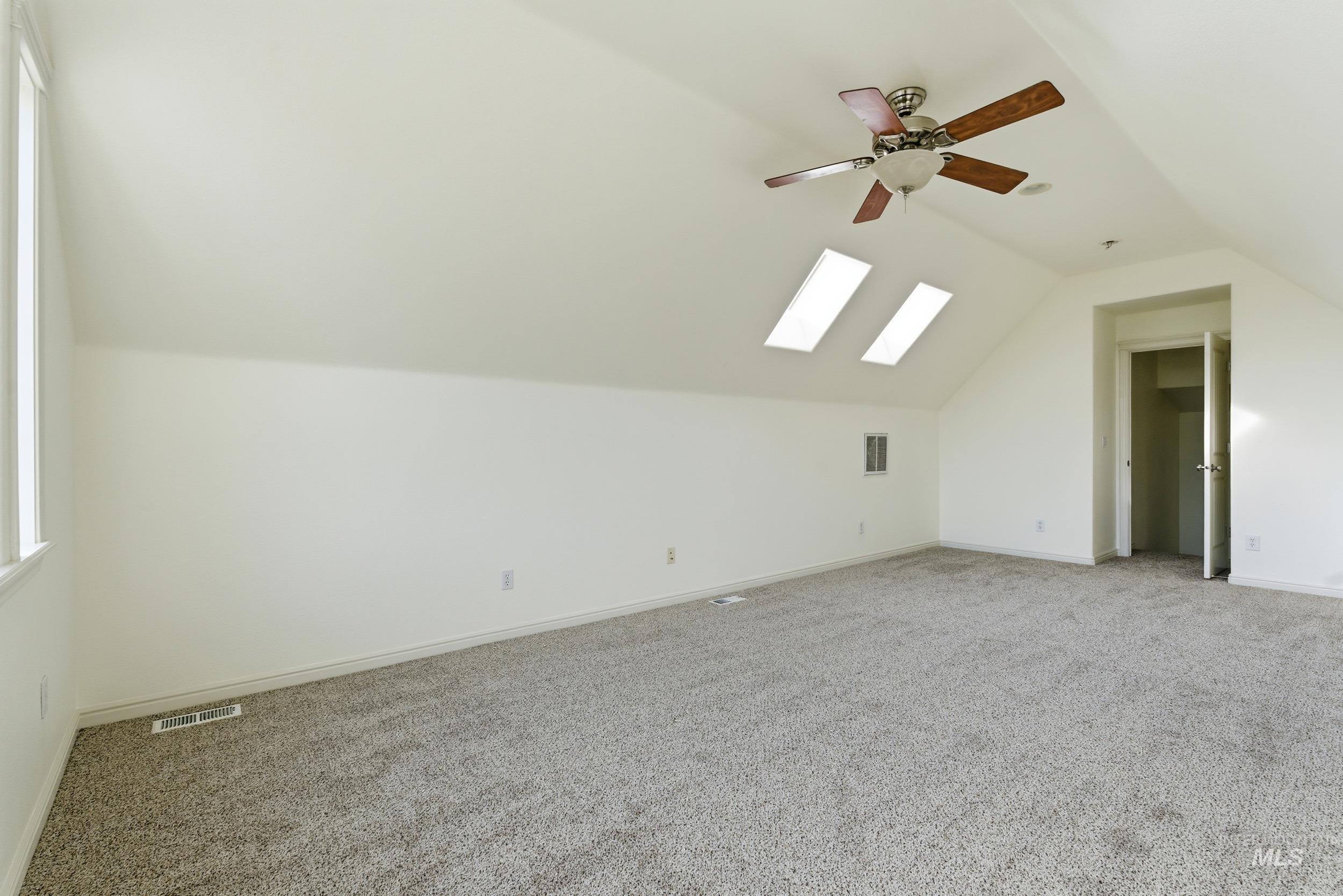 Bonus room with carpet floors, a skylight, lofted ceiling, and ceiling fan
