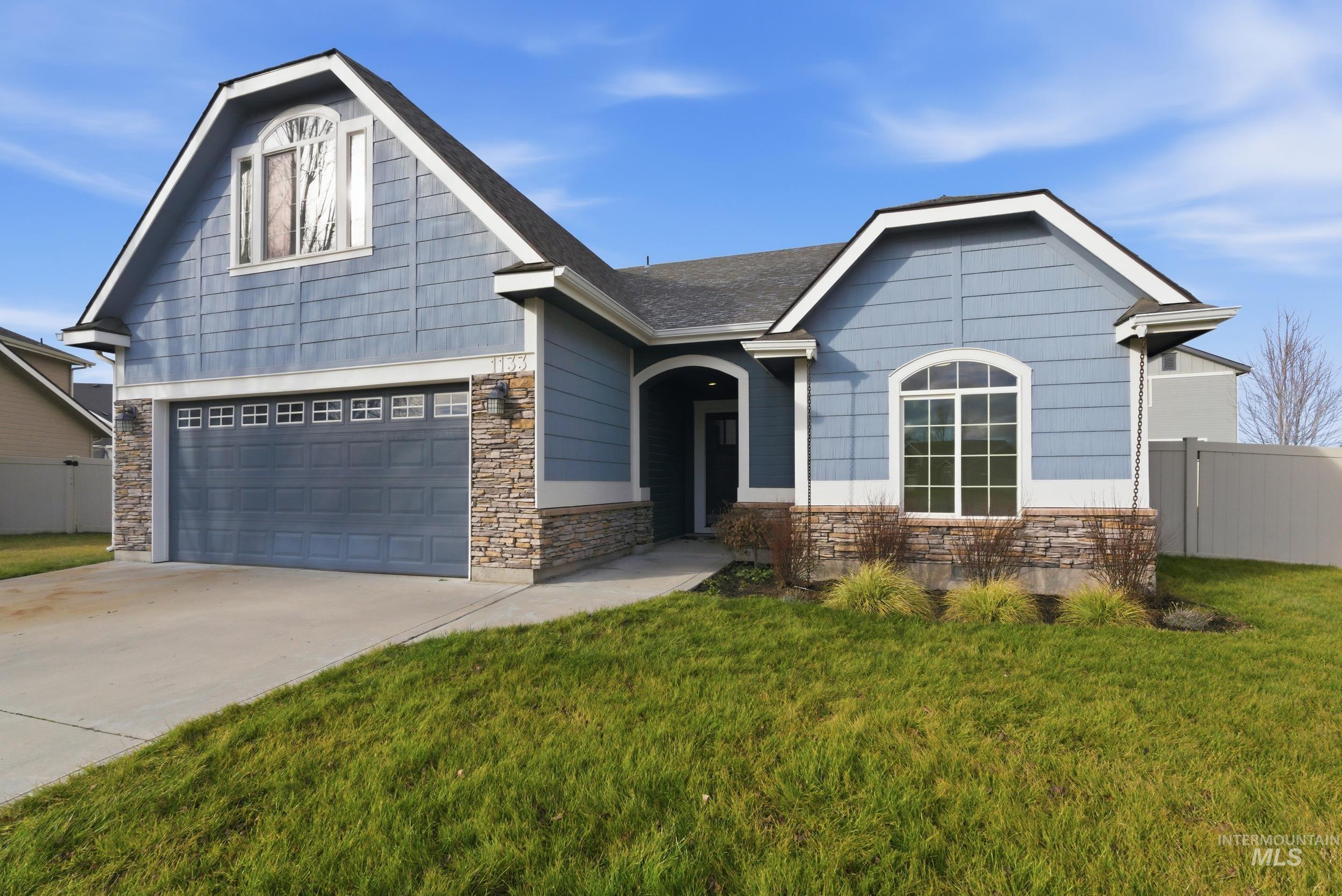 View of front of home with stone siding, driveway, and an attached garage