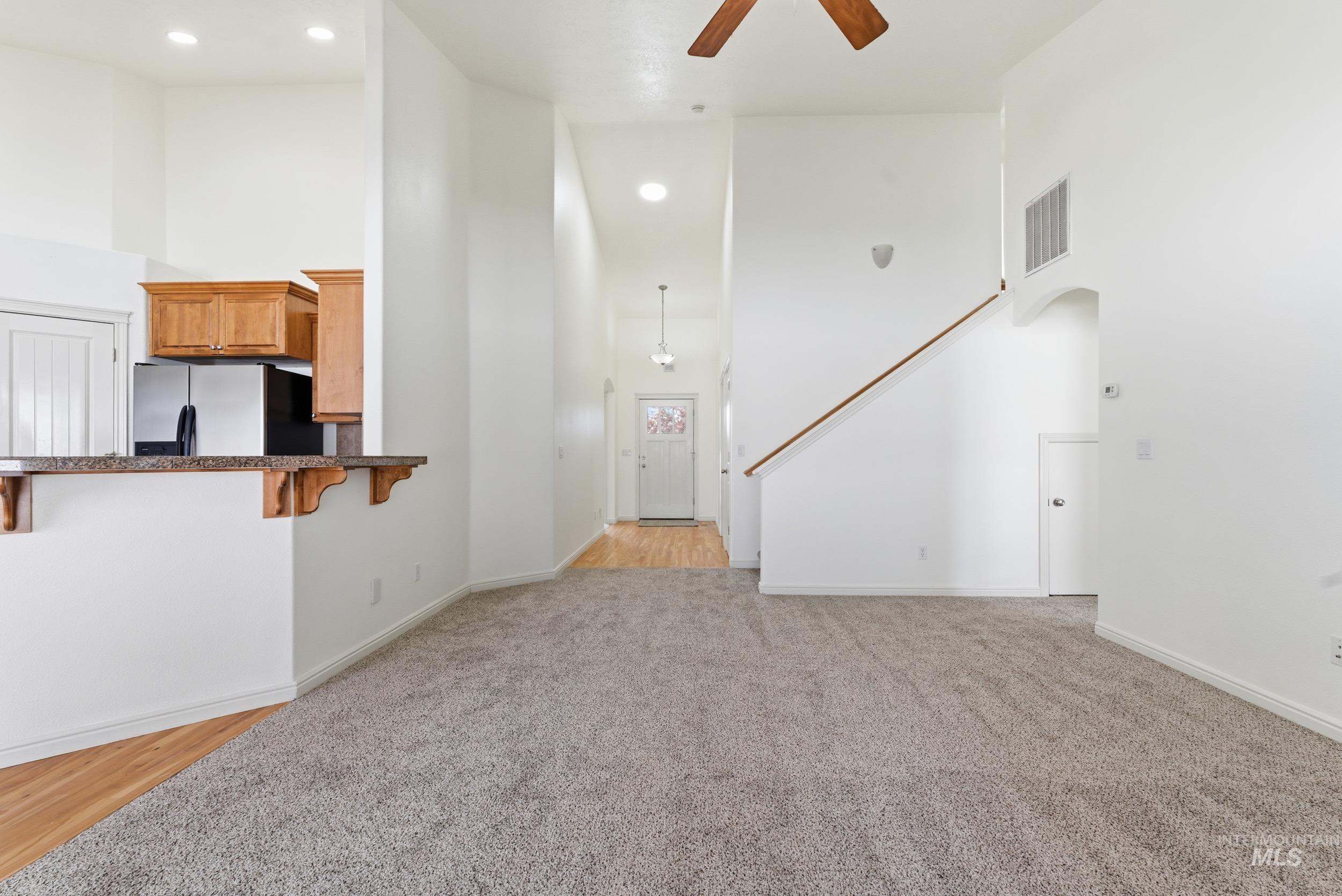 Unfurnished living room with a high ceiling, a ceiling fan, light carpet, and recessed lighting