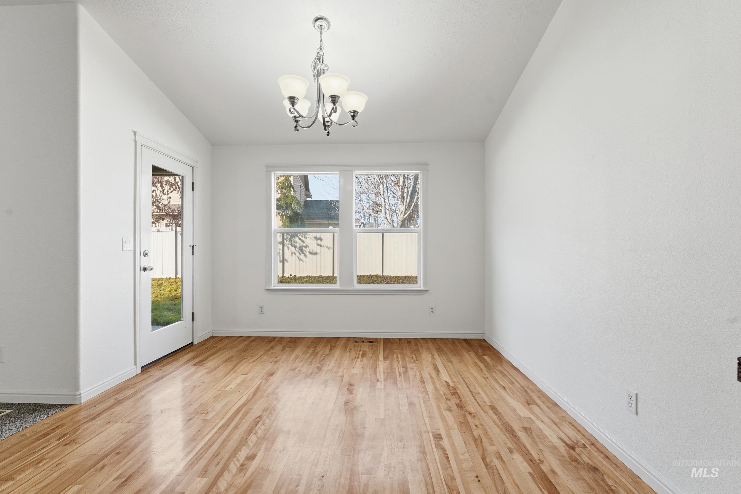 Unfurnished dining area with a chandelier and light wood-style flooring