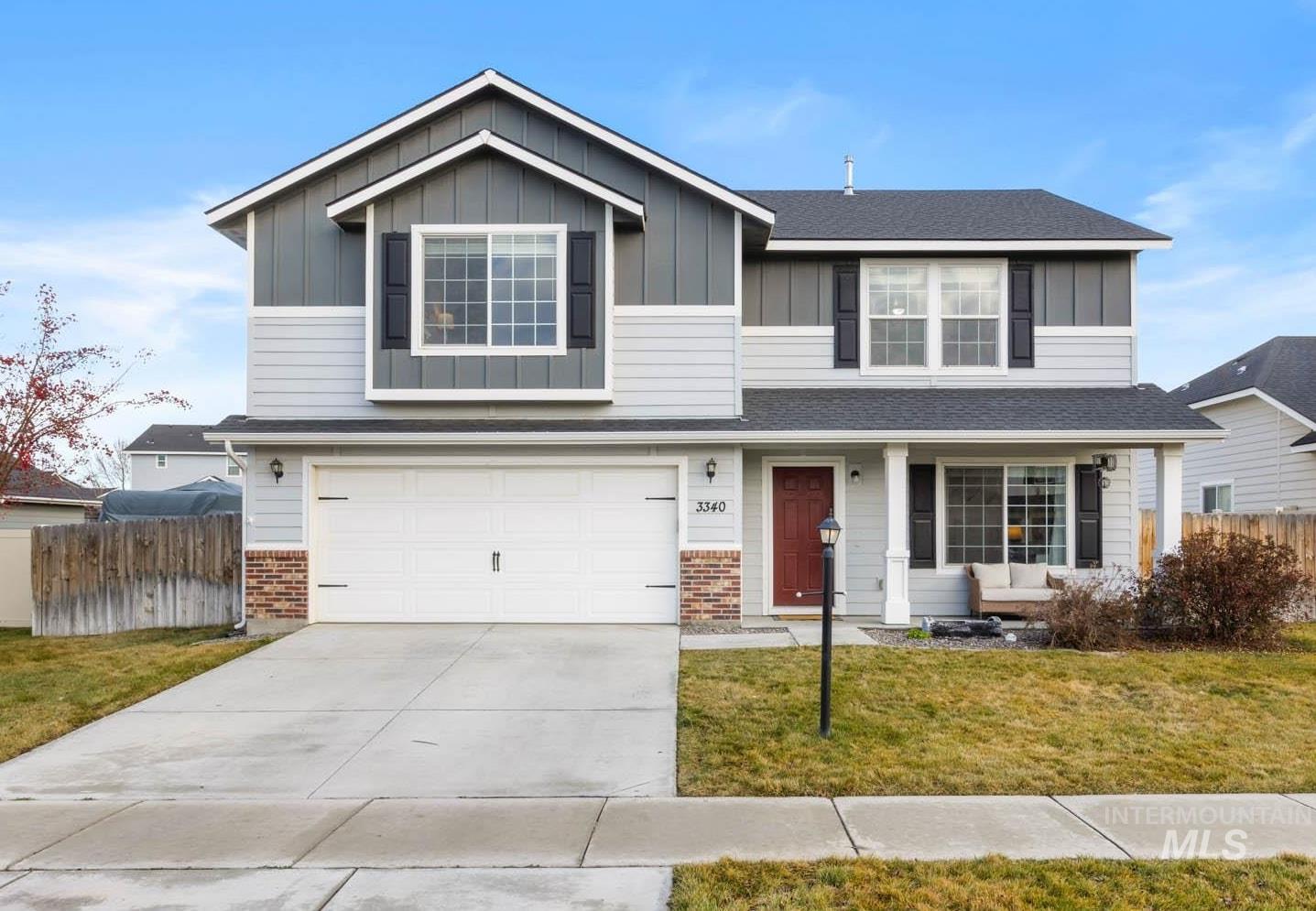 Traditional-style house featuring driveway, board and batten siding, an attached garage, a porch, and brick siding