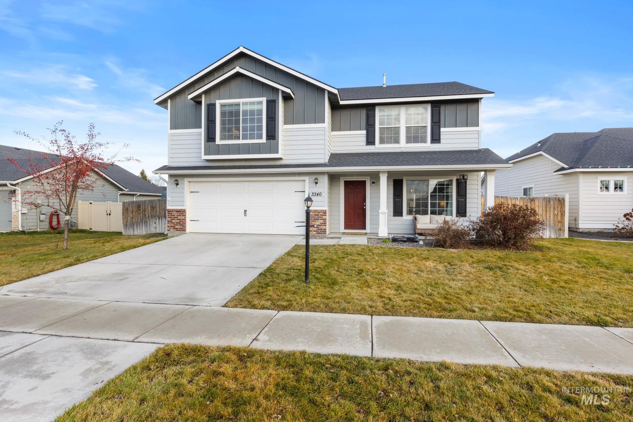 Traditional home featuring a garage, driveway, board and batten siding, covered porch, and brick siding