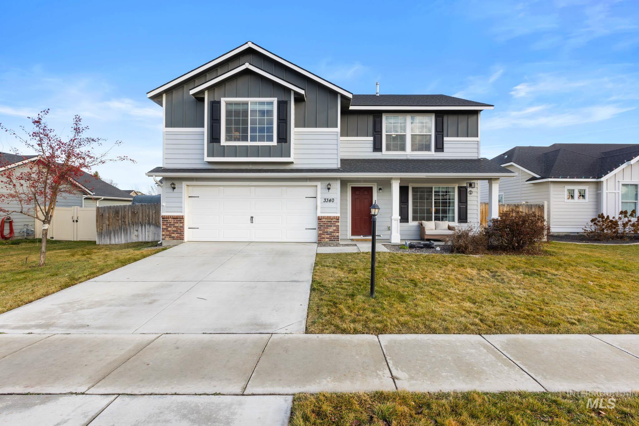 Traditional-style home with driveway, an attached garage, board and batten siding, covered porch, and brick siding