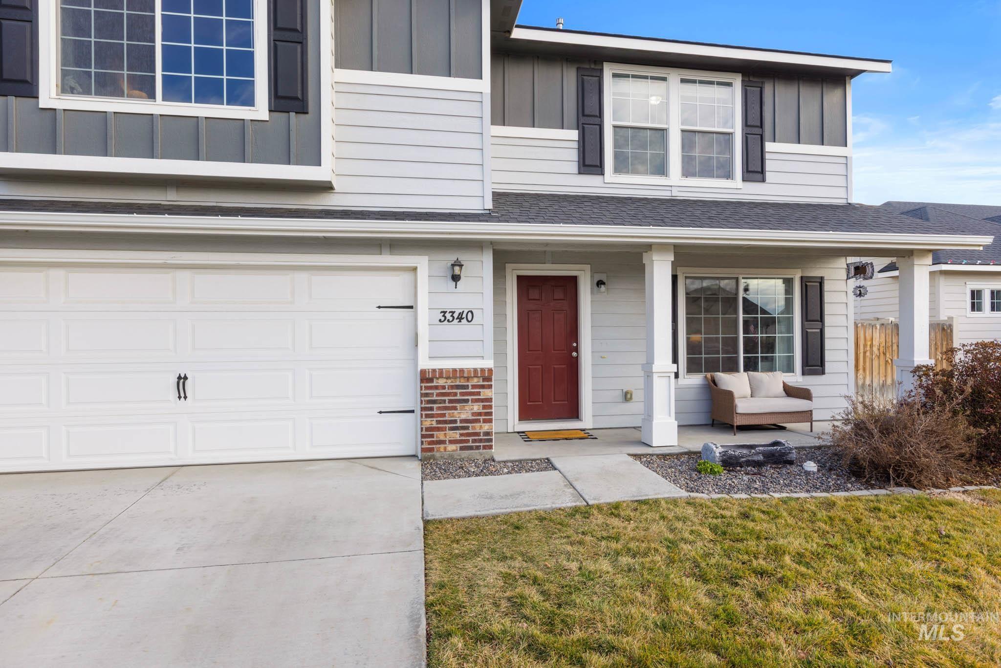 Traditional-style house with board and batten siding, a porch, driveway, and a garage