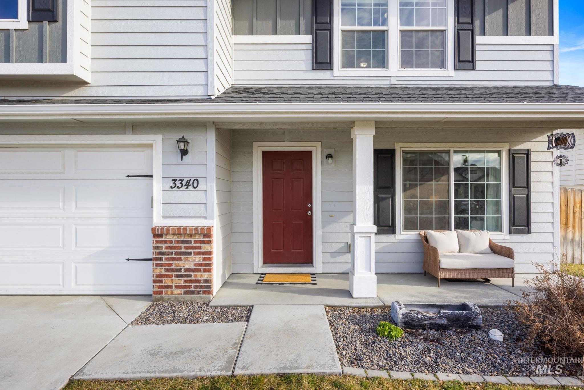 Property entrance featuring covered porch, brick siding, and a shingled roof