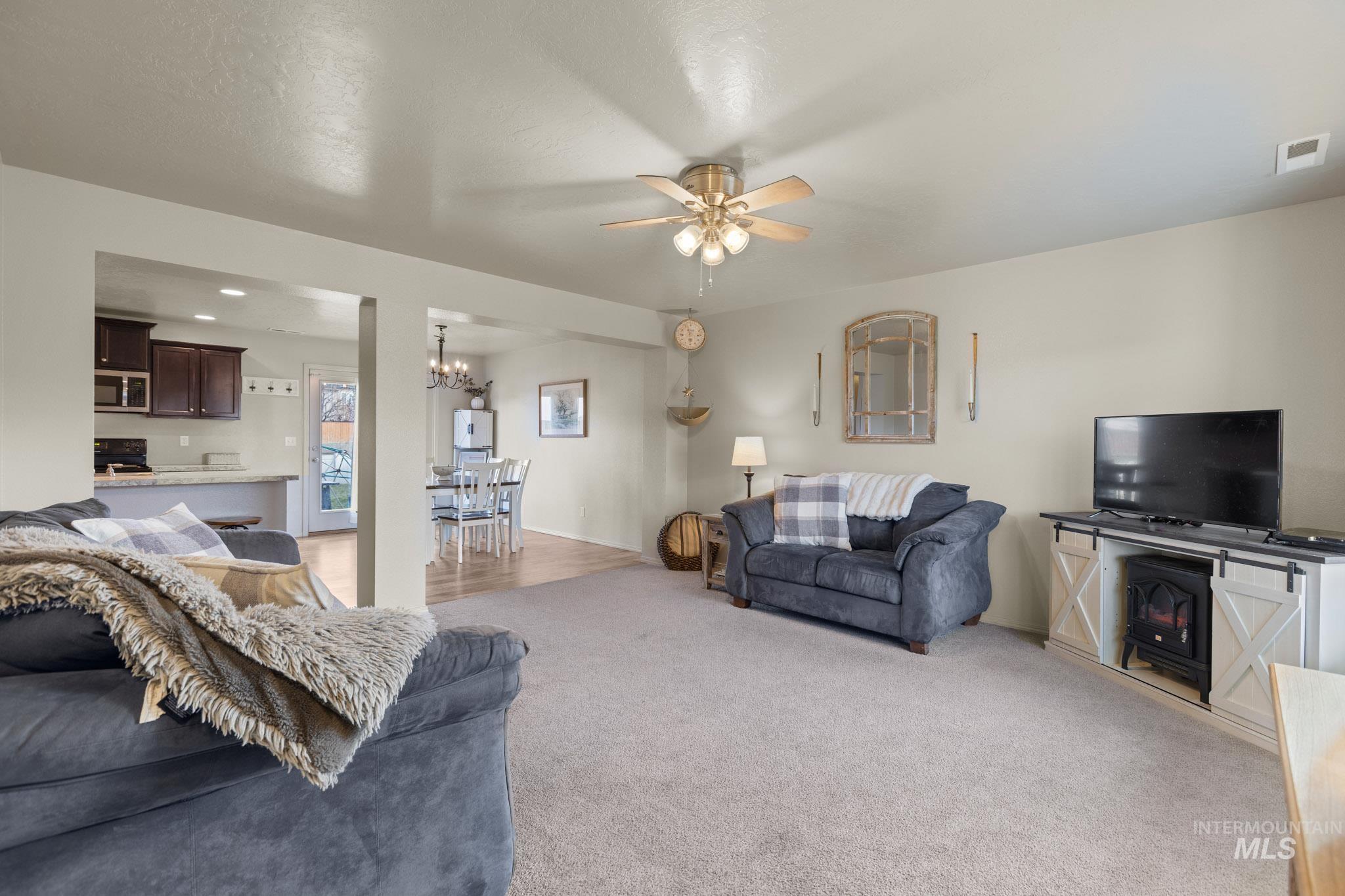 Living room featuring a ceiling fan, light carpet, and a chandelier