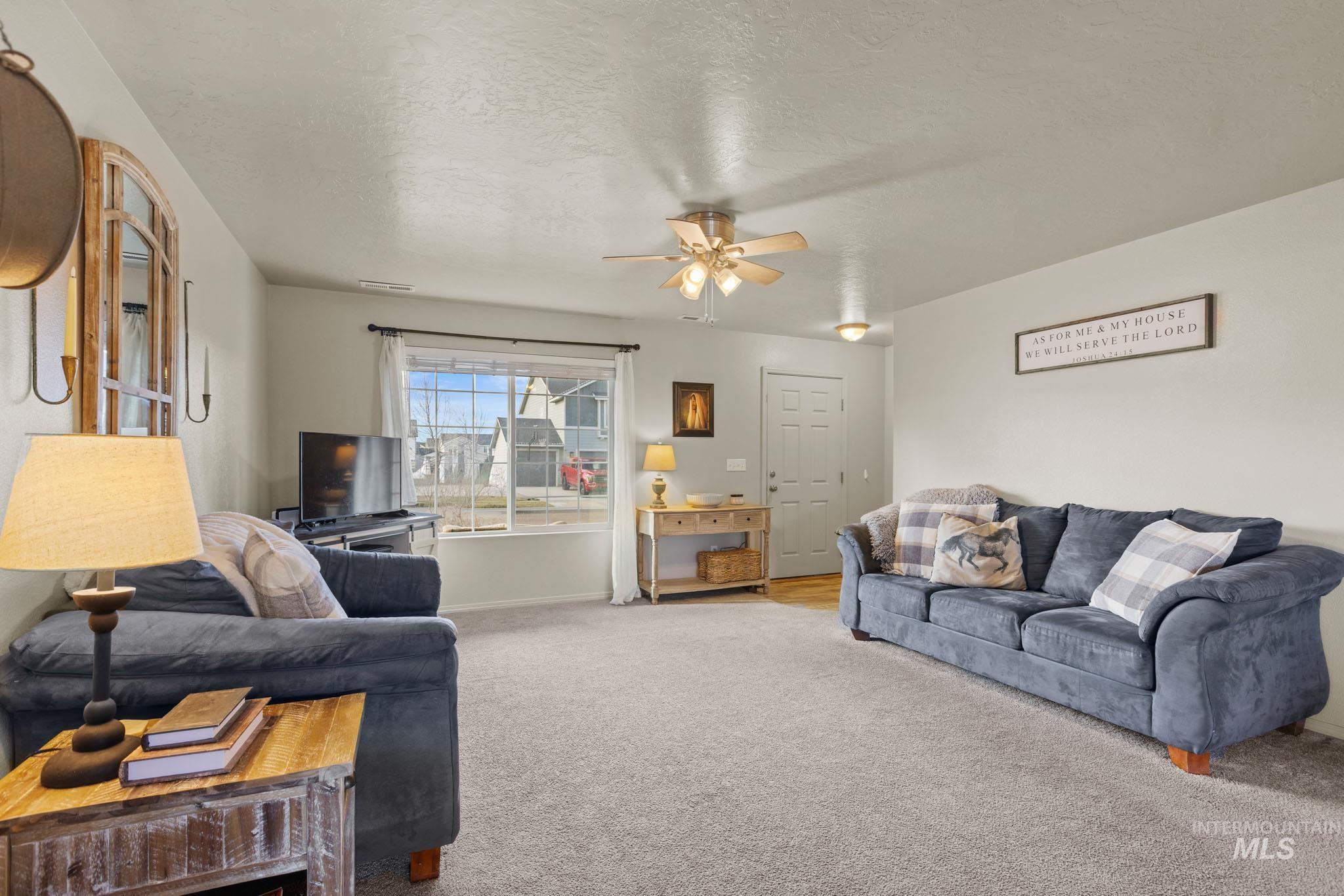 Carpeted living area with a textured ceiling and a ceiling fan