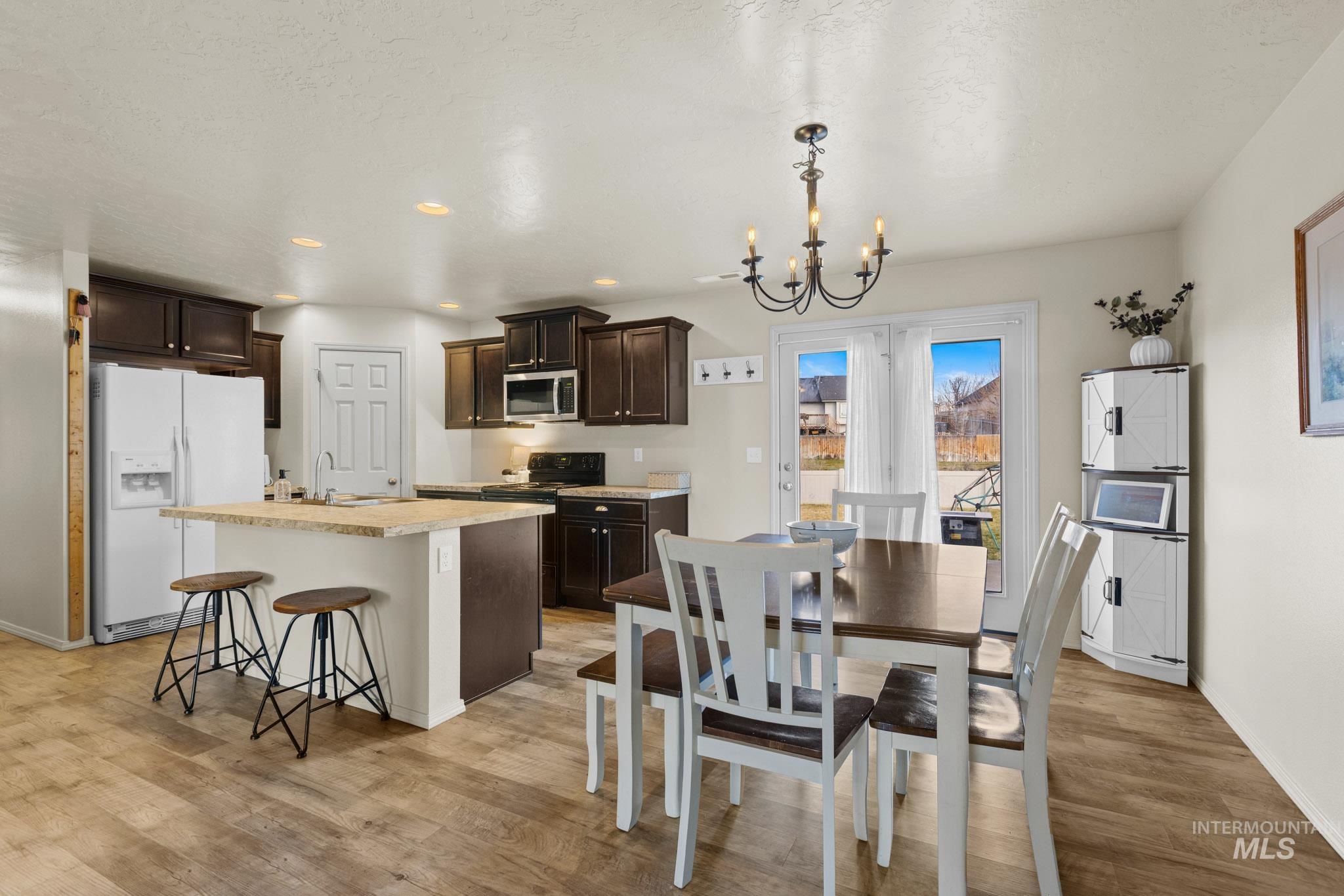 Dining room with a chandelier, light wood finished floors, and recessed lighting