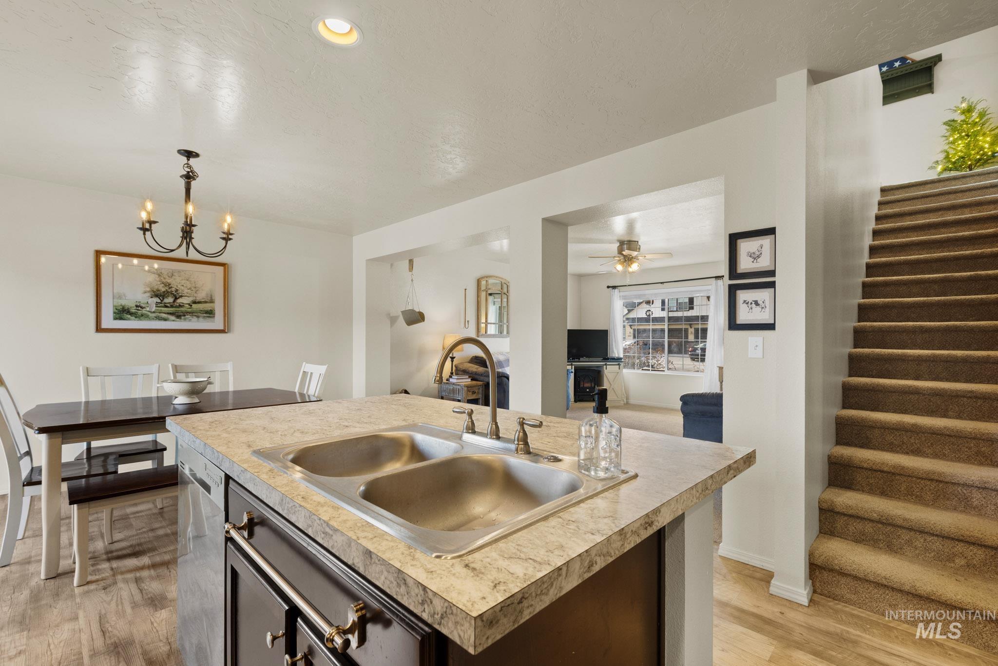 Kitchen with light countertops, a center island with sink, decorative light fixtures, open floor plan, and light wood-style floors