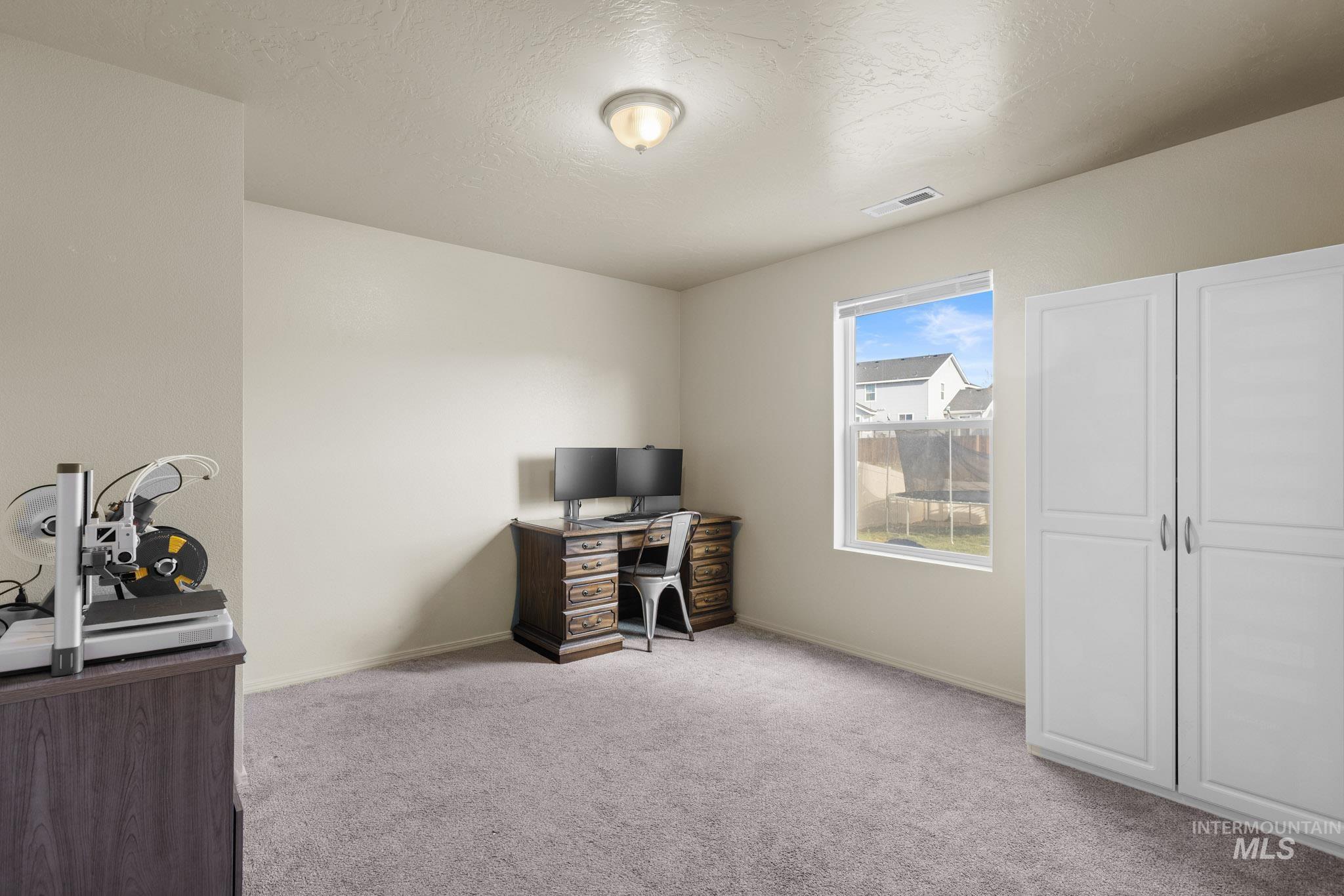 Home office featuring light carpet and a textured ceiling