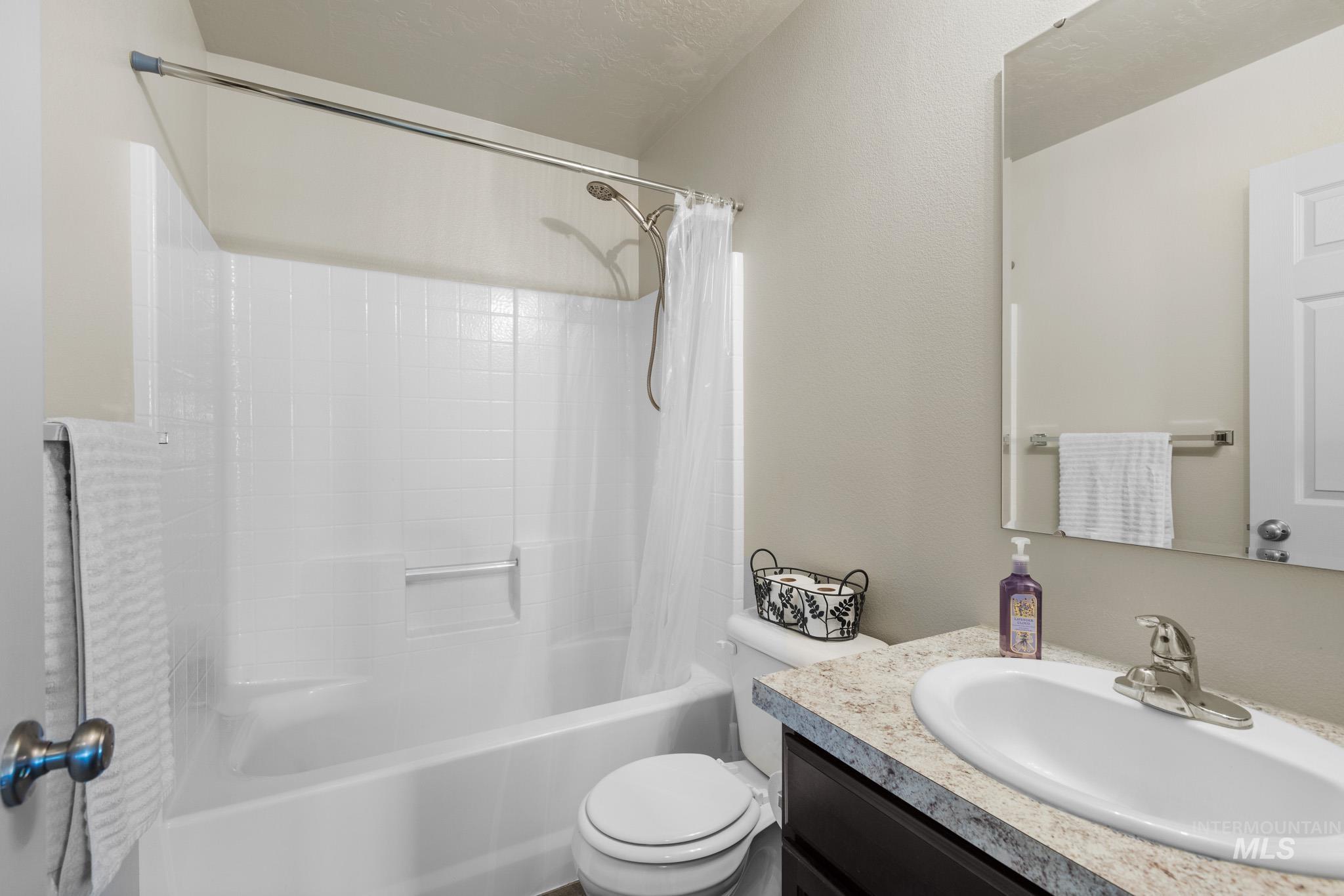 Bathroom featuring shower / tub combo with curtain, vanity, and a textured ceiling
