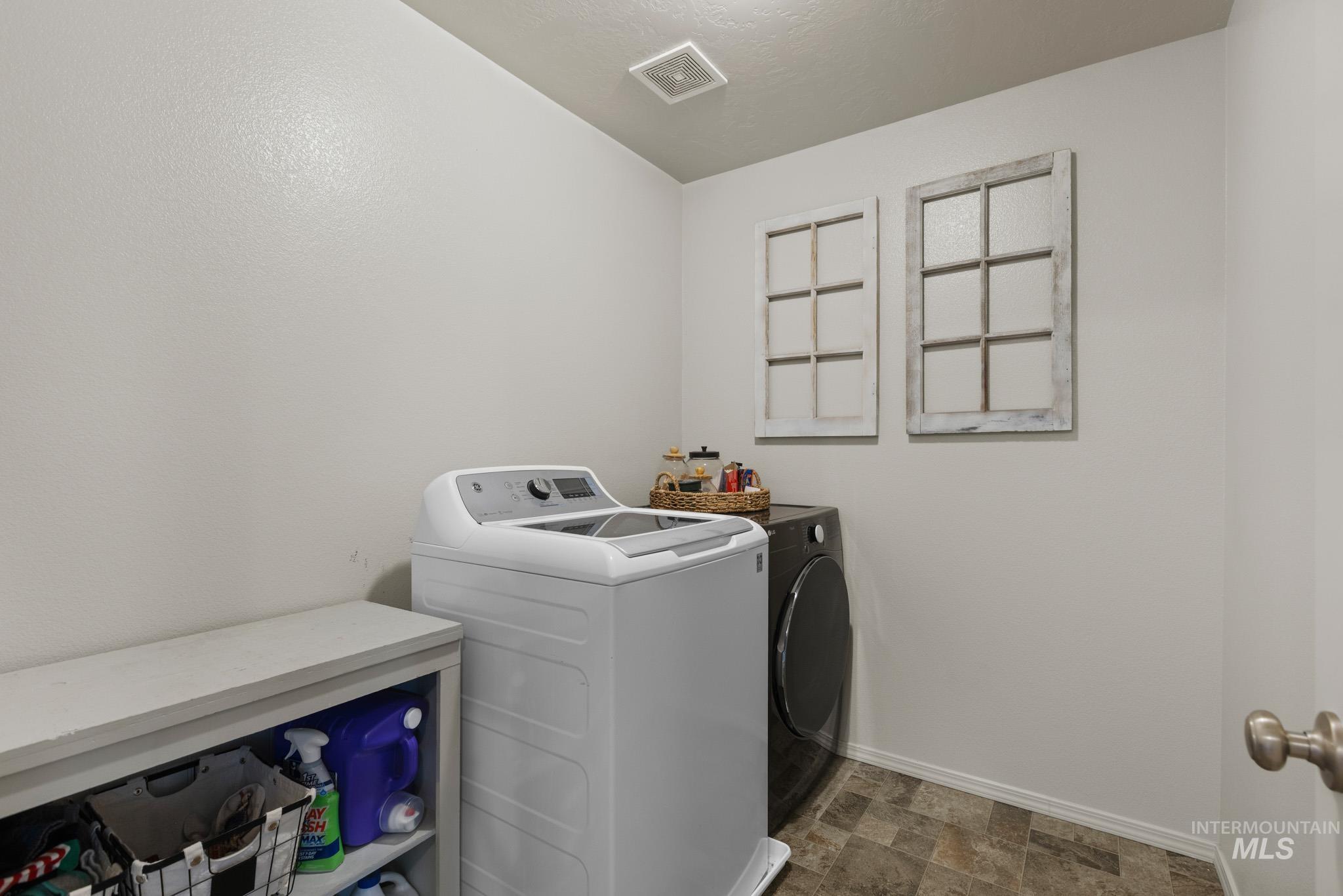 Laundry area with stone finish flooring and washer and dryer