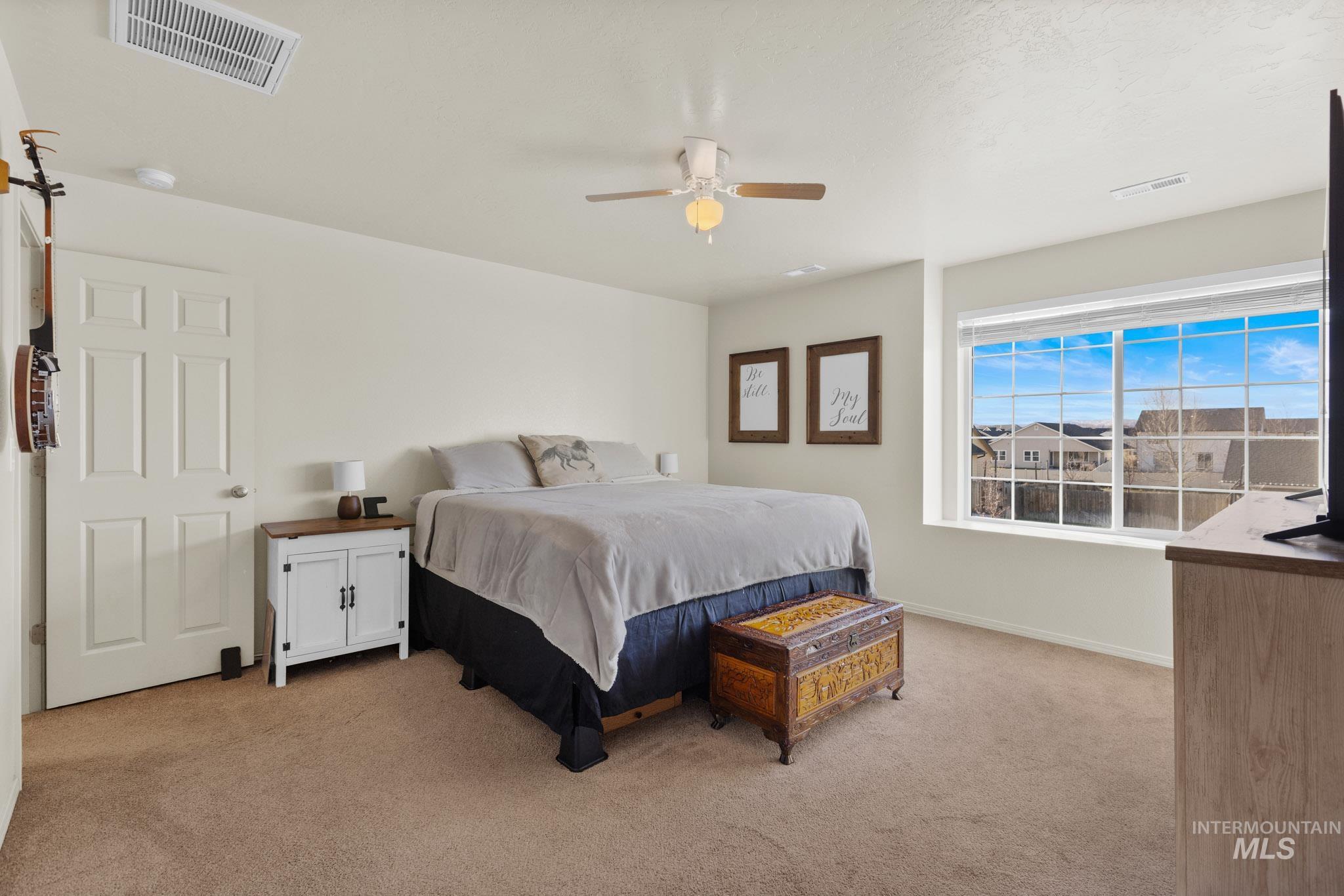 Bedroom with light carpet and a ceiling fan