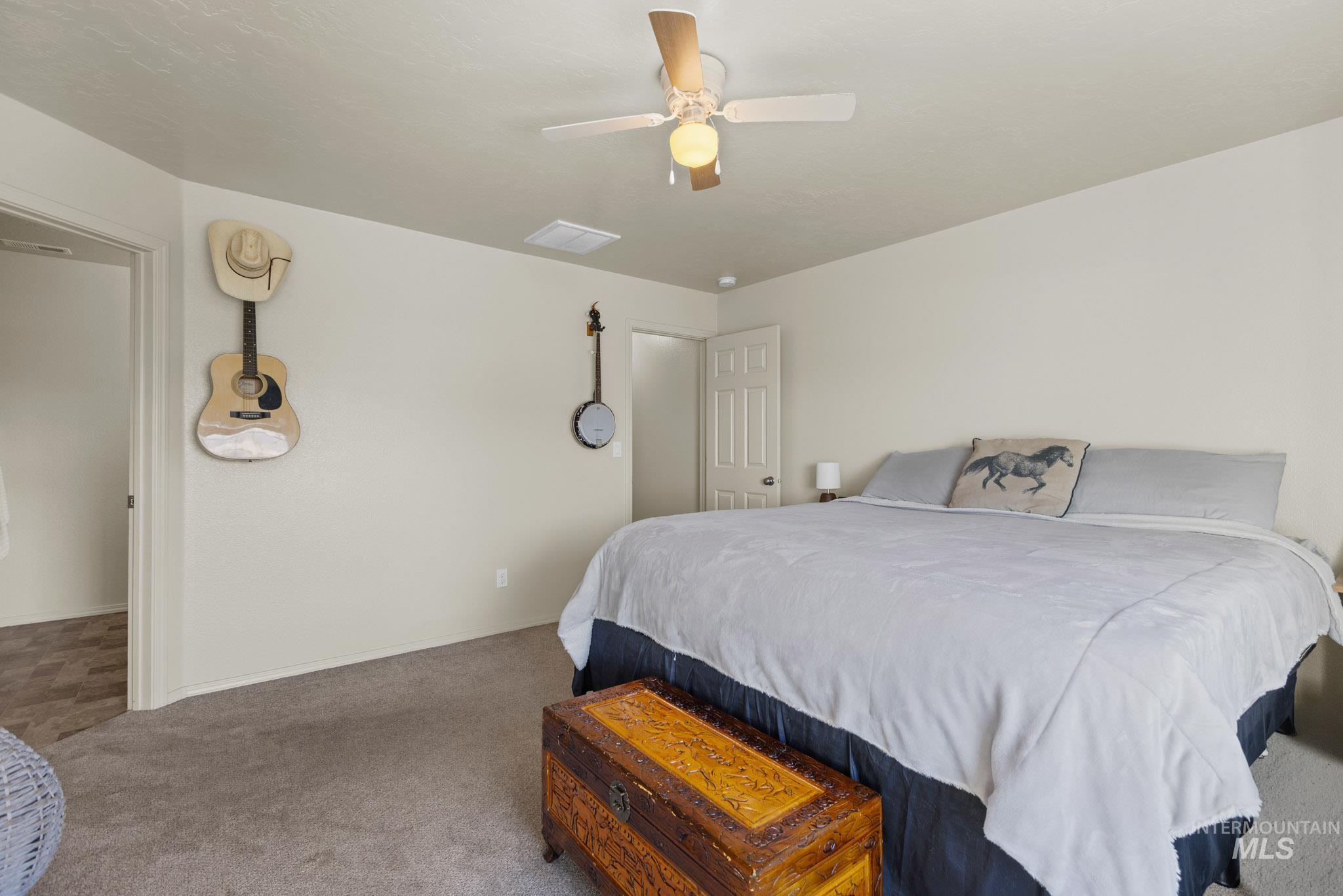 Carpeted bedroom with ceiling fan and baseboards