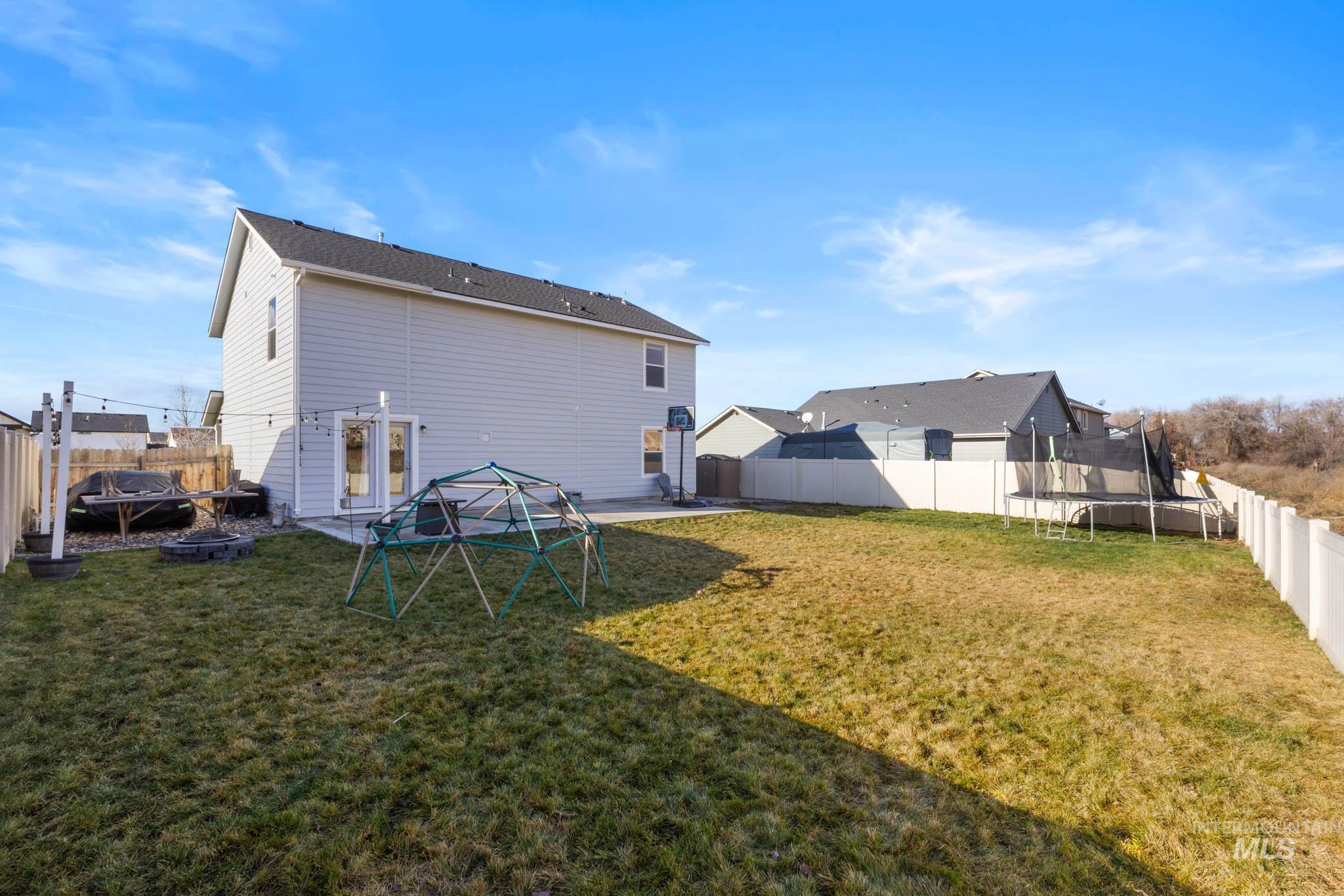 Back of house with a trampoline, a fenced backyard, and a patio