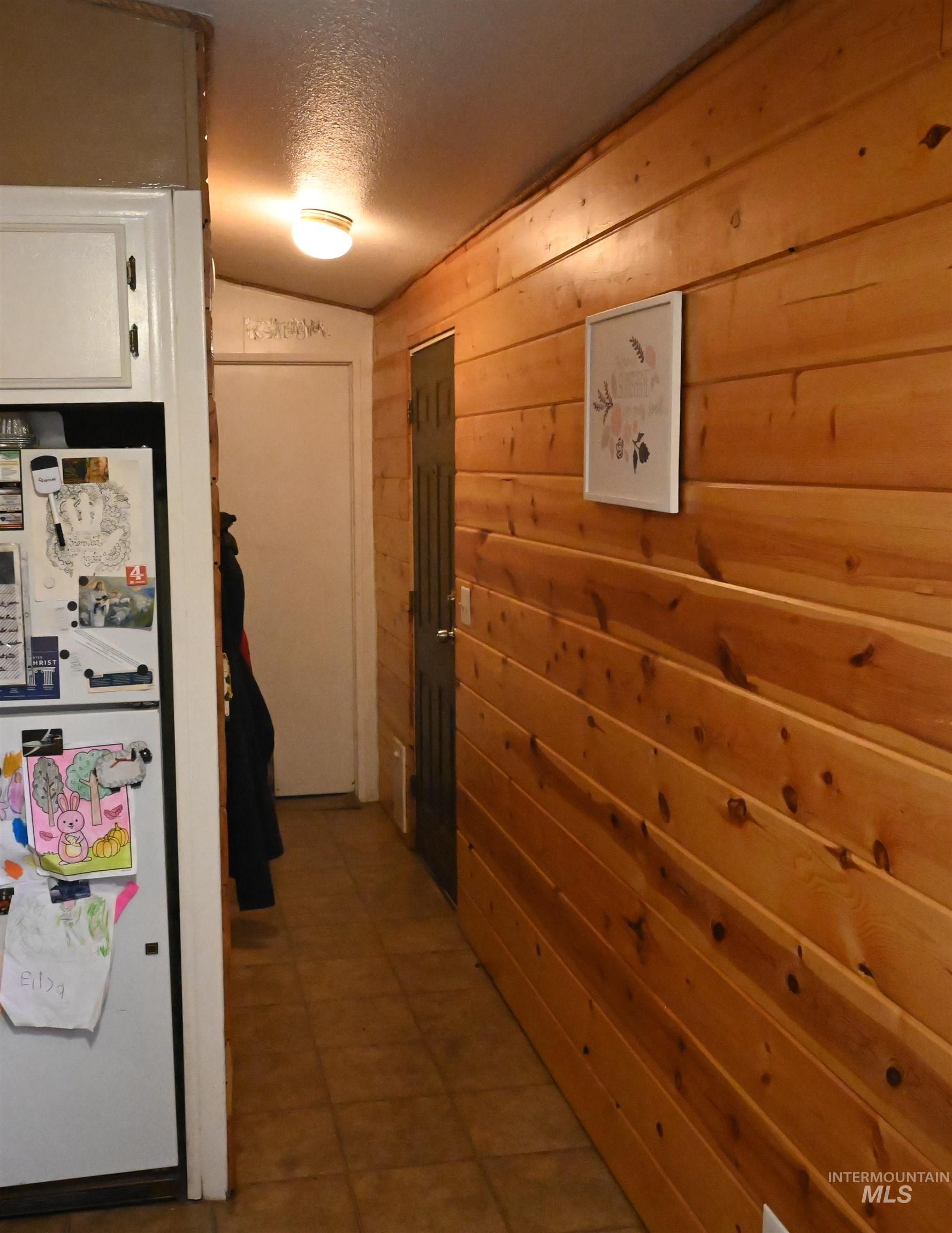 Corridor with wooden walls, a textured ceiling, and vaulted ceiling
