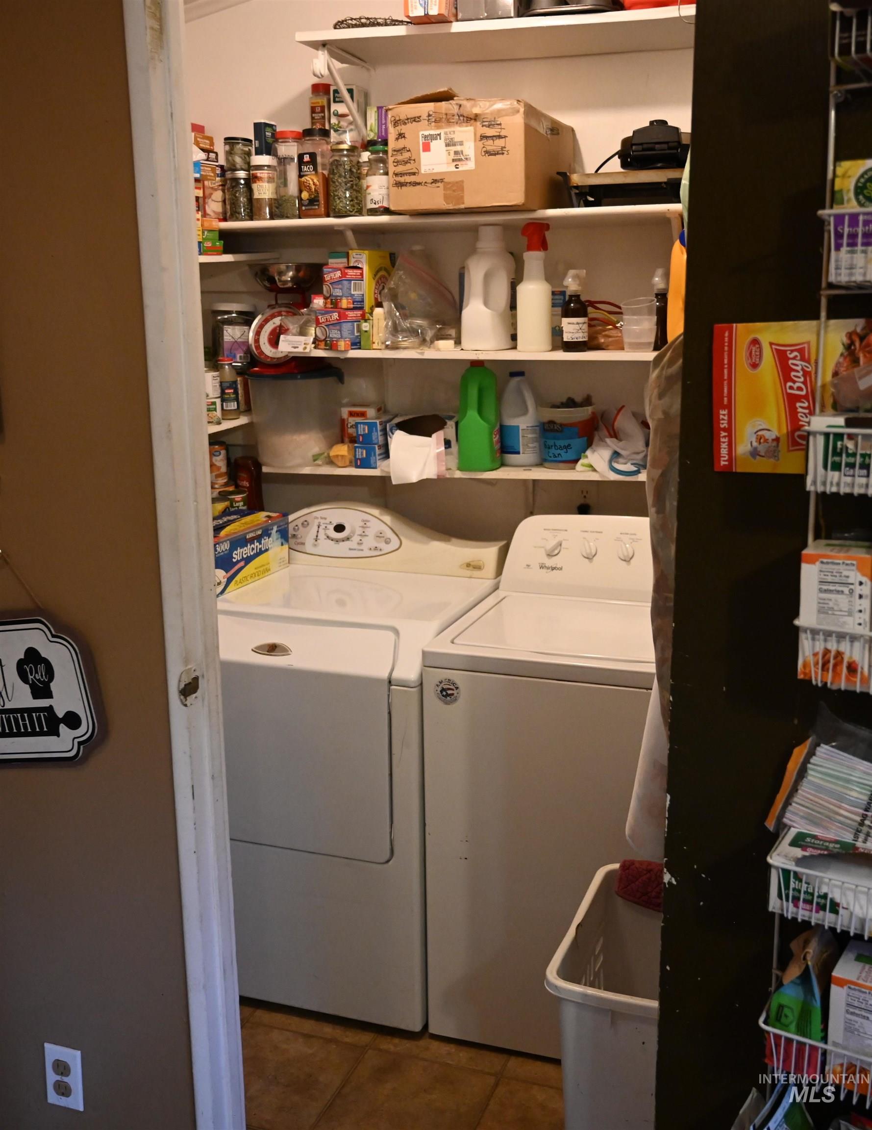 Washroom with washer and clothes dryer and dark tile patterned floors