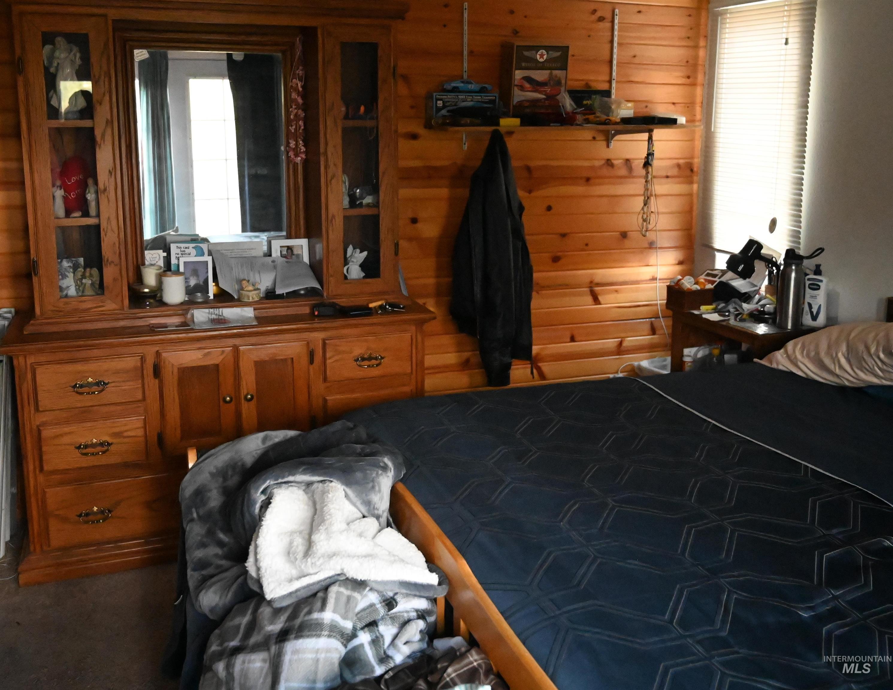 Bedroom featuring wood walls and dark colored carpet