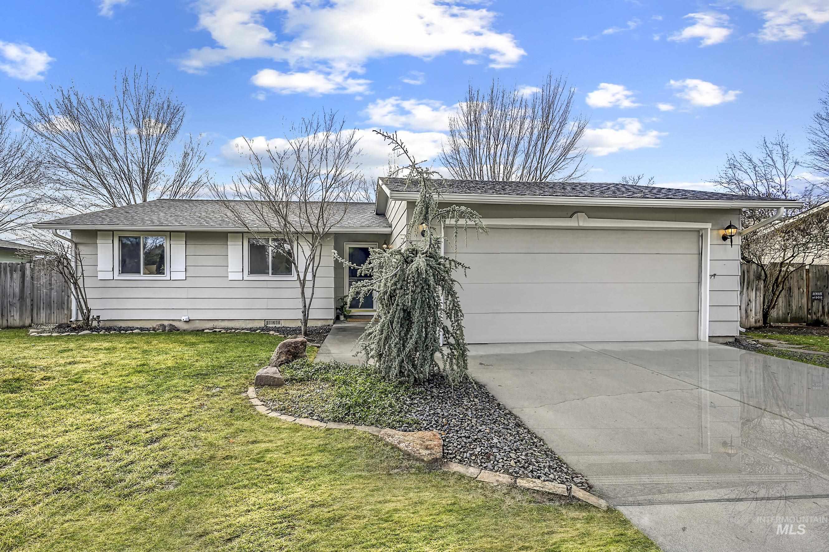 Single story home featuring an attached garage, driveway, and a shingled roof