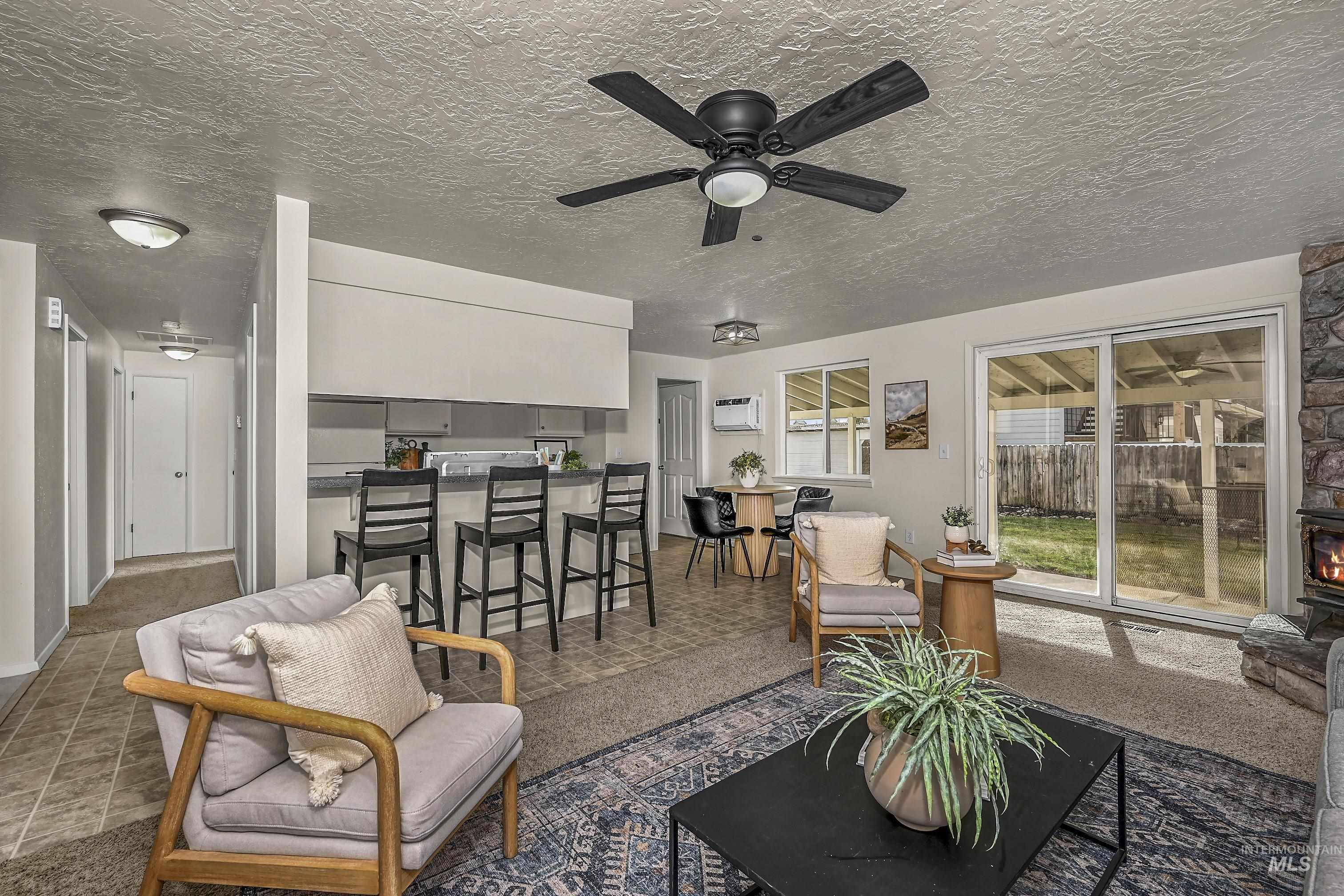 Living room featuring a textured ceiling, a ceiling fan, and an AC wall unit