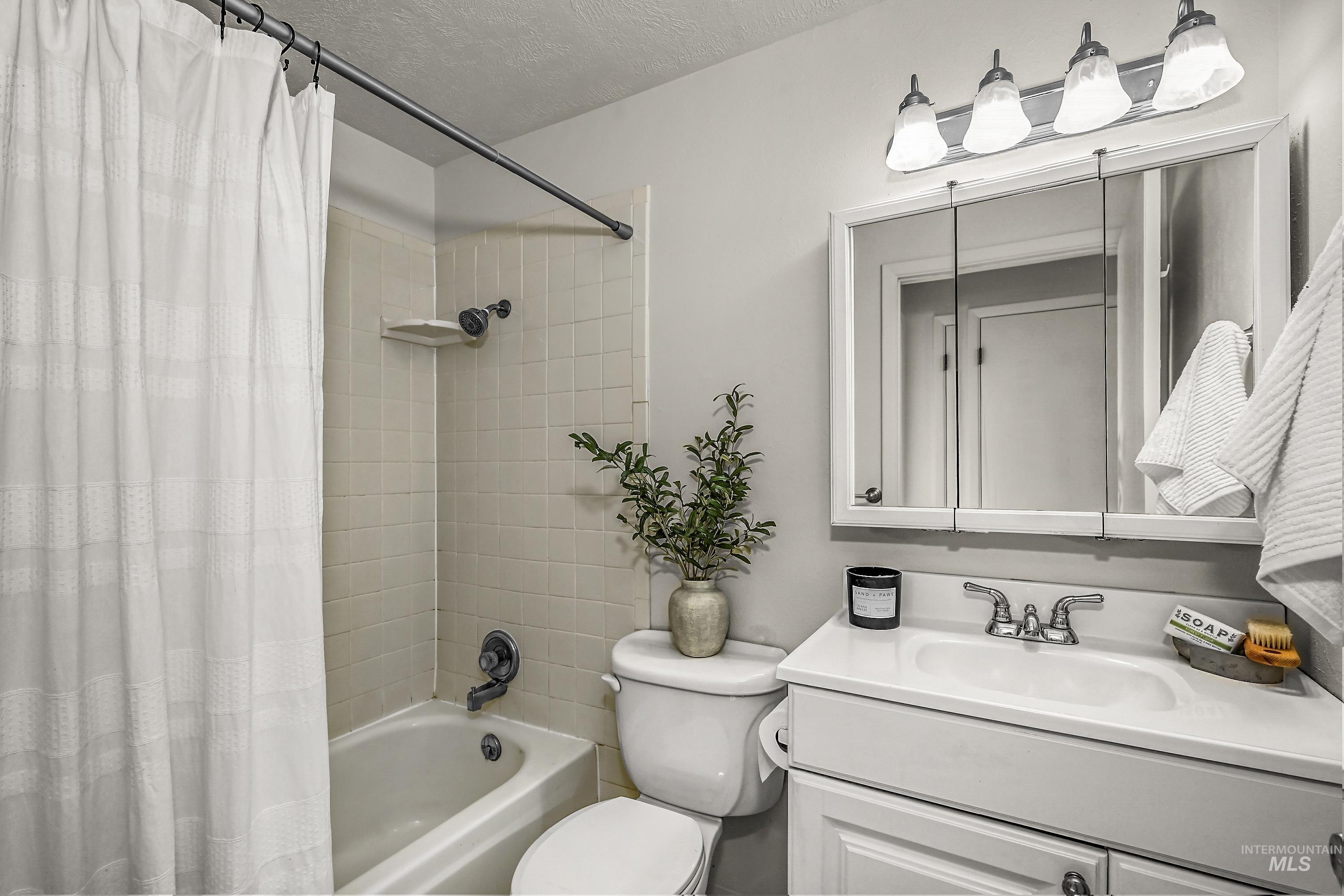 Full bathroom with shower / bath combo with shower curtain, vanity, and a textured ceiling