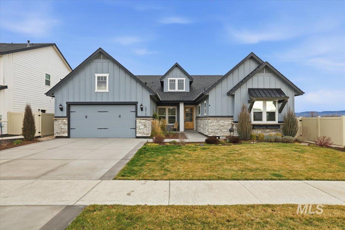 View of front of property featuring board and batten siding, stone siding, driveway, and a garage