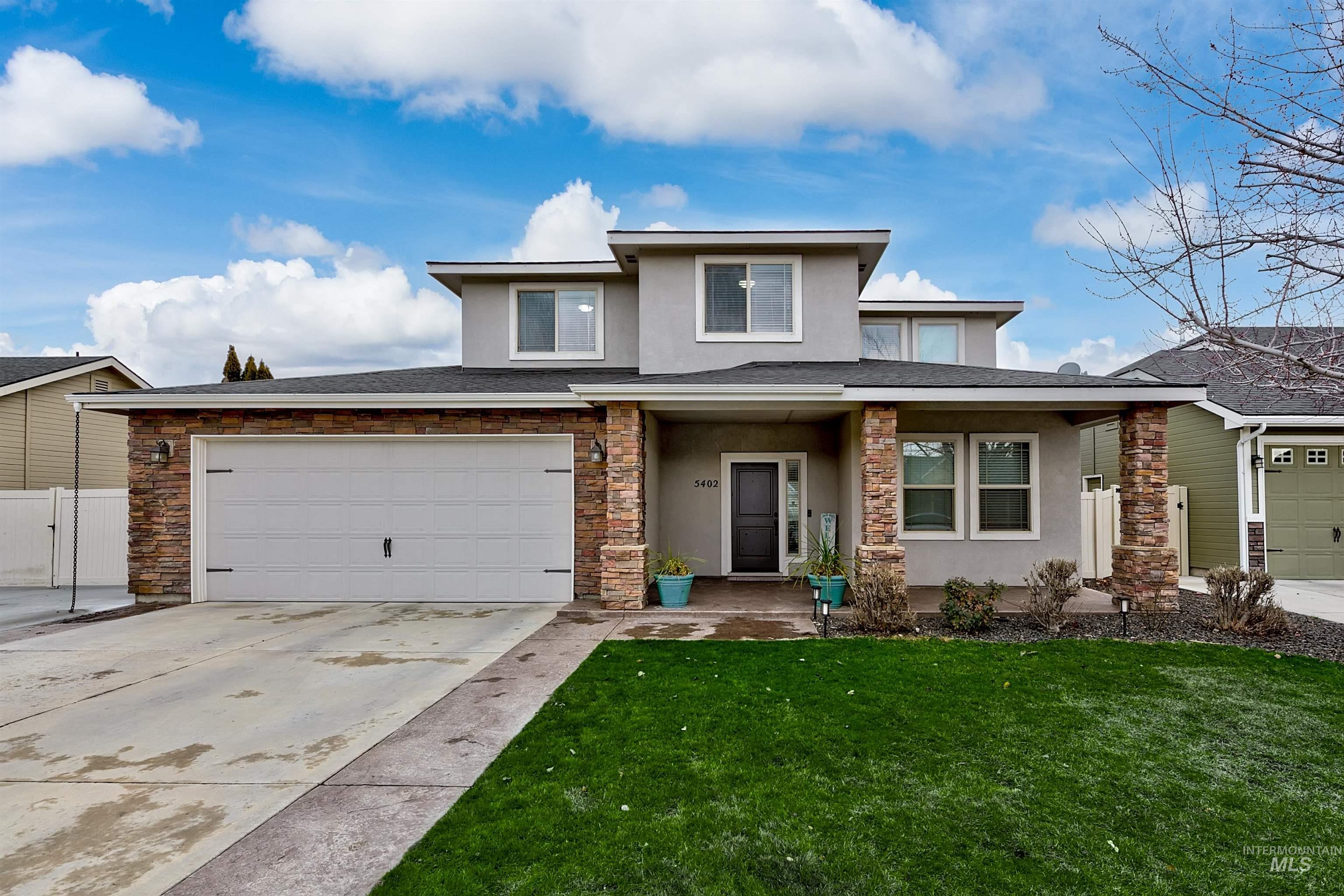 Prairie-style house with stucco siding, covered porch, concrete driveway, an attached garage, and stone siding