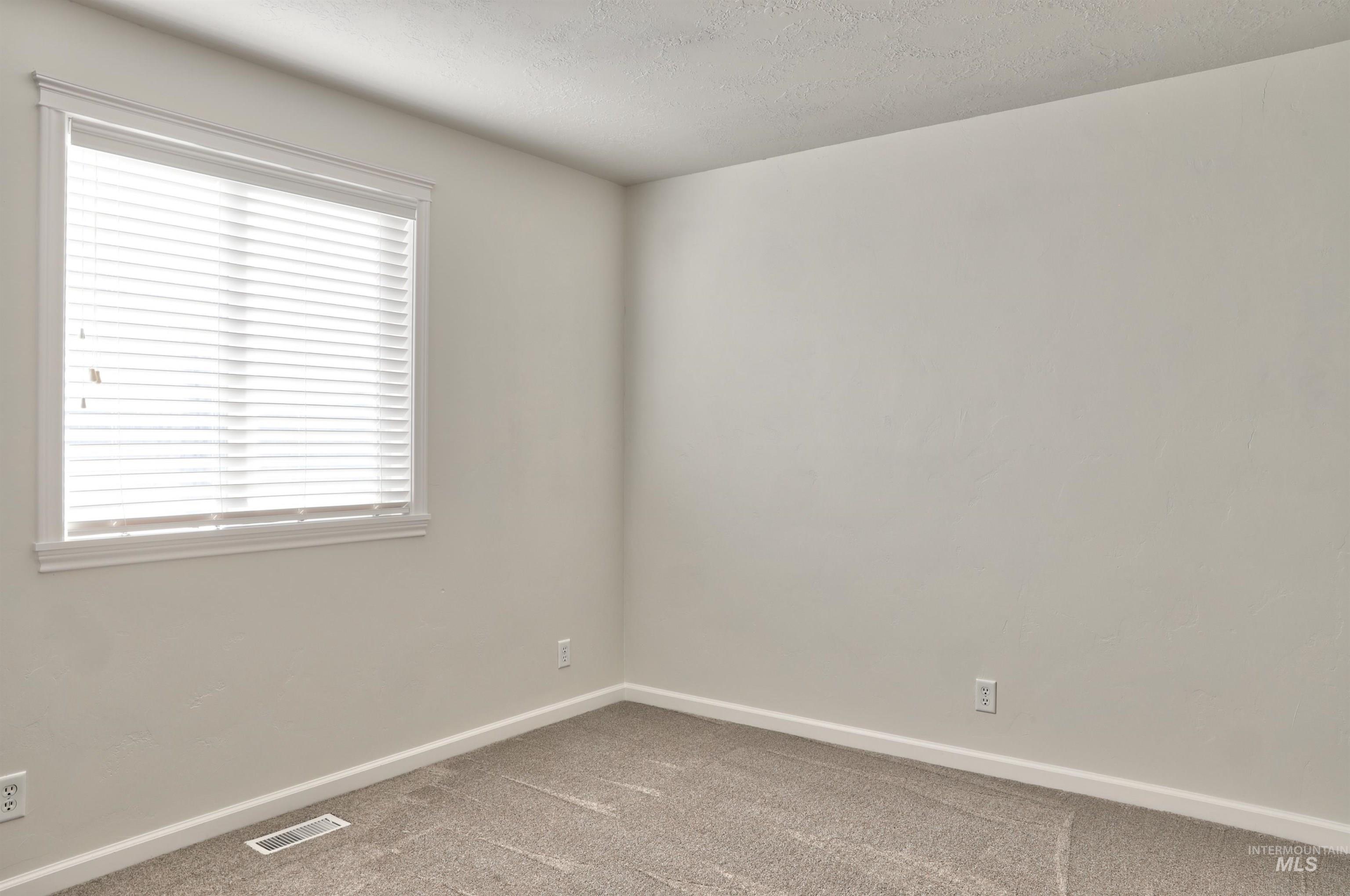 Carpeted empty room with baseboards and a textured ceiling