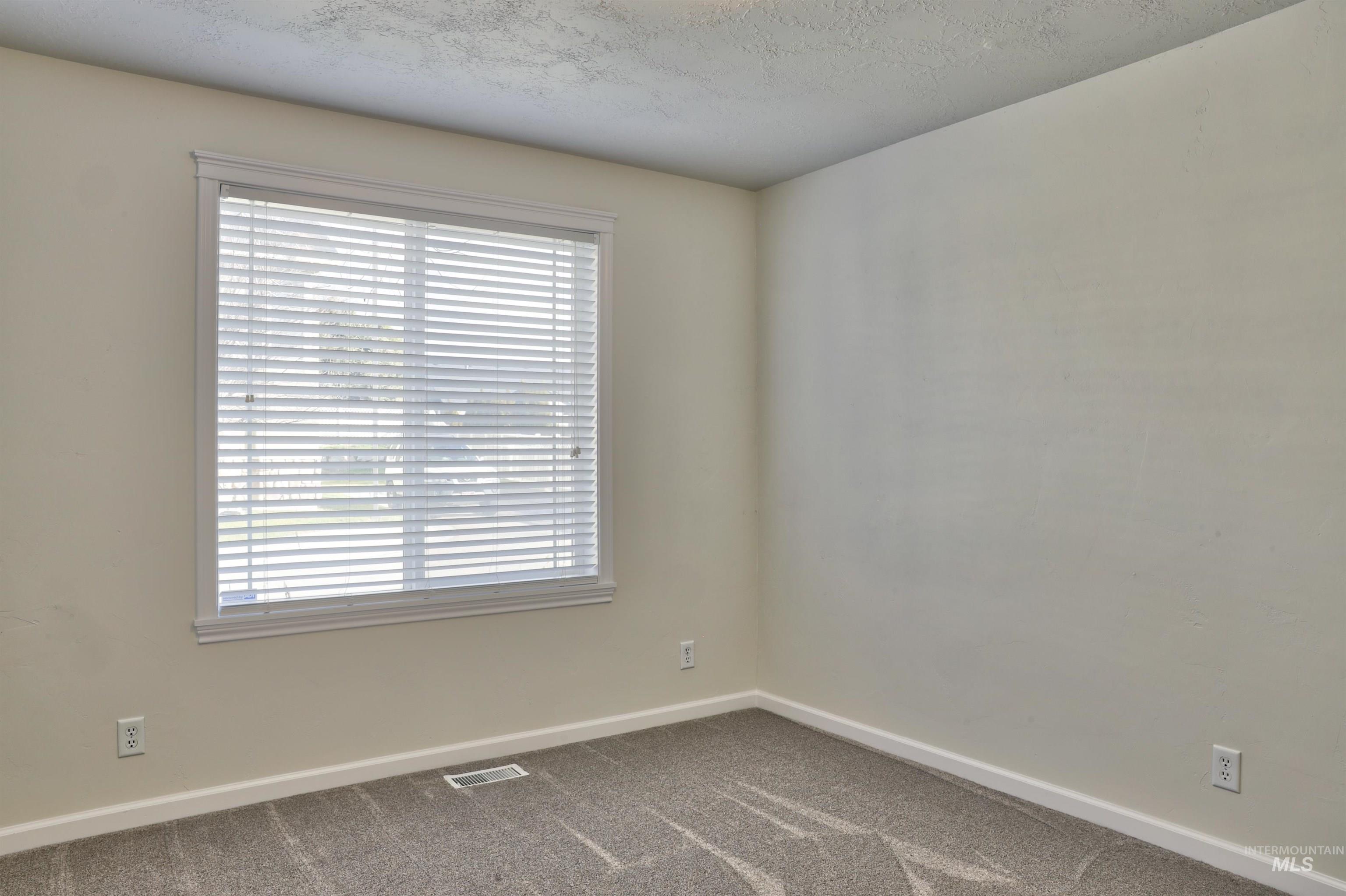 Carpeted spare room with baseboards and a textured ceiling