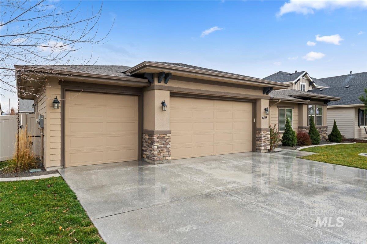 View of front of house with stone siding, concrete driveway, a garage, and roof with shingles