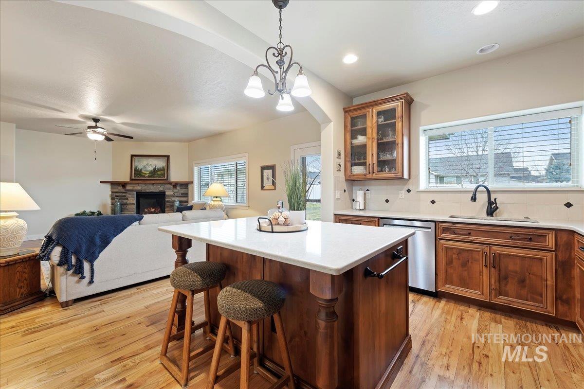 Kitchen with brown cabinets, decorative light fixtures, tasteful backsplash, and a kitchen breakfast bar