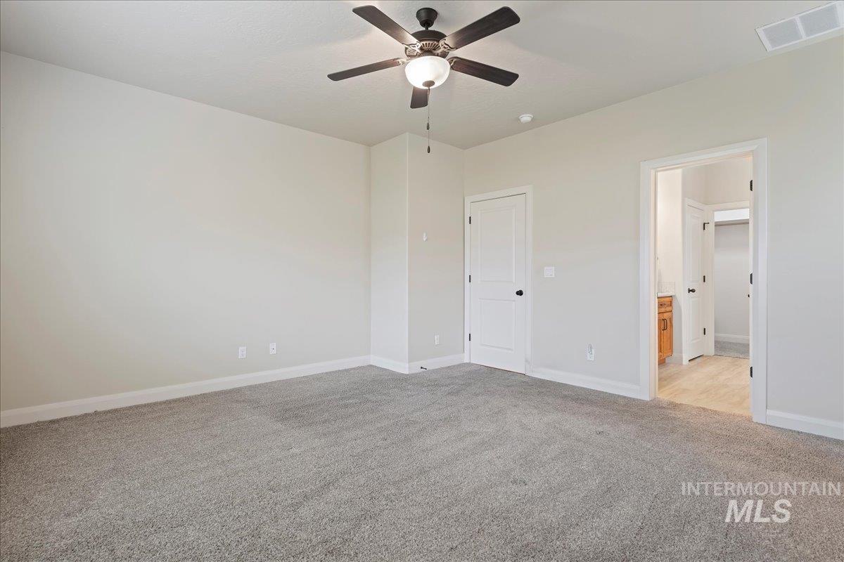 Unfurnished bedroom featuring light carpet, ceiling fan, and connected bathroom