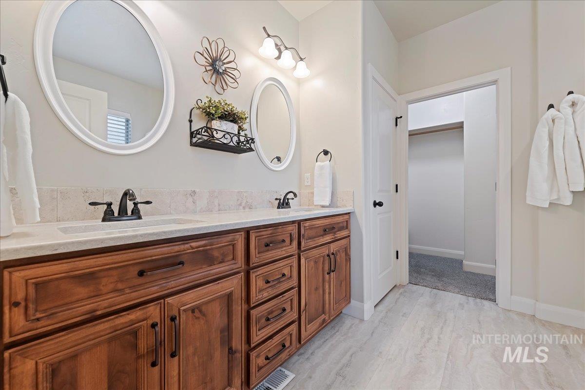 Full bathroom with double vanity and light wood finished floors