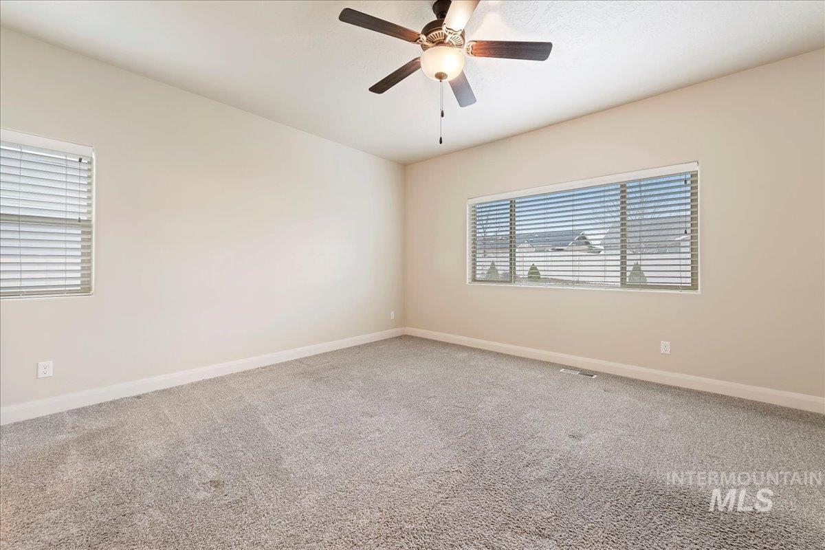 Carpeted spare room featuring baseboards and ceiling fan