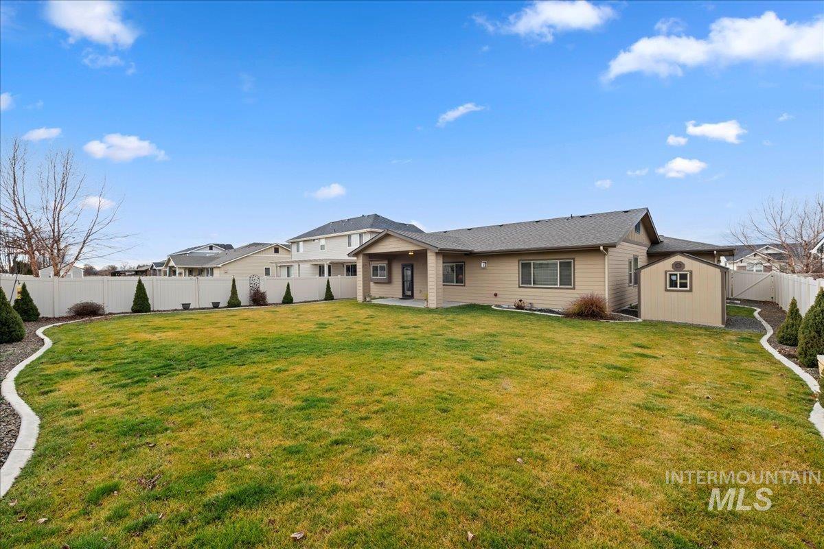 Back of property with a fenced backyard, a patio area, and a storage shed