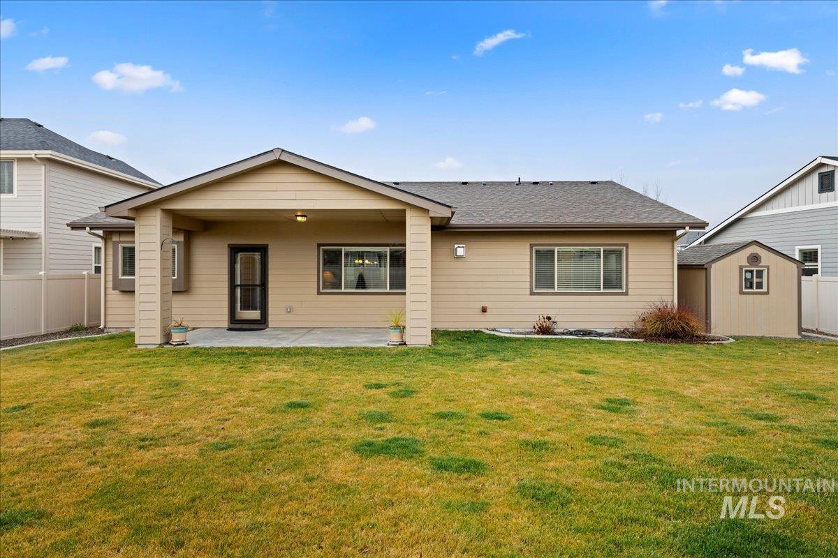 Back of property with a patio area, a shingled roof, and a storage shed