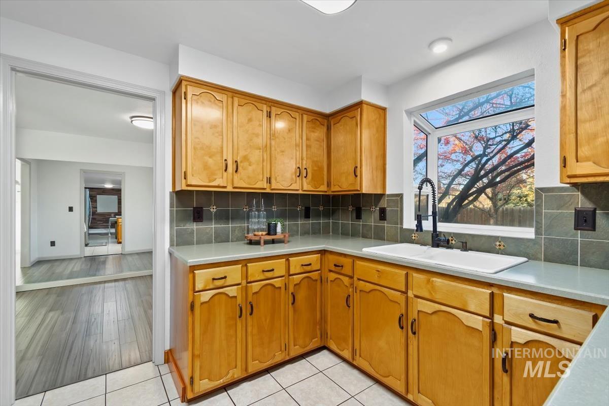 Kitchen featuring light countertops, brown cabinets, tasteful backsplash, and light tile patterned floors