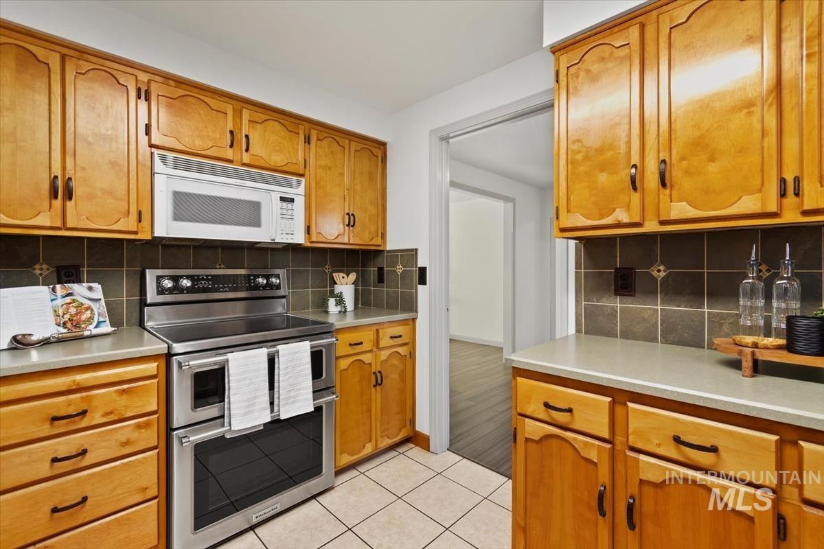 Kitchen with range with two ovens, white microwave, and light countertops