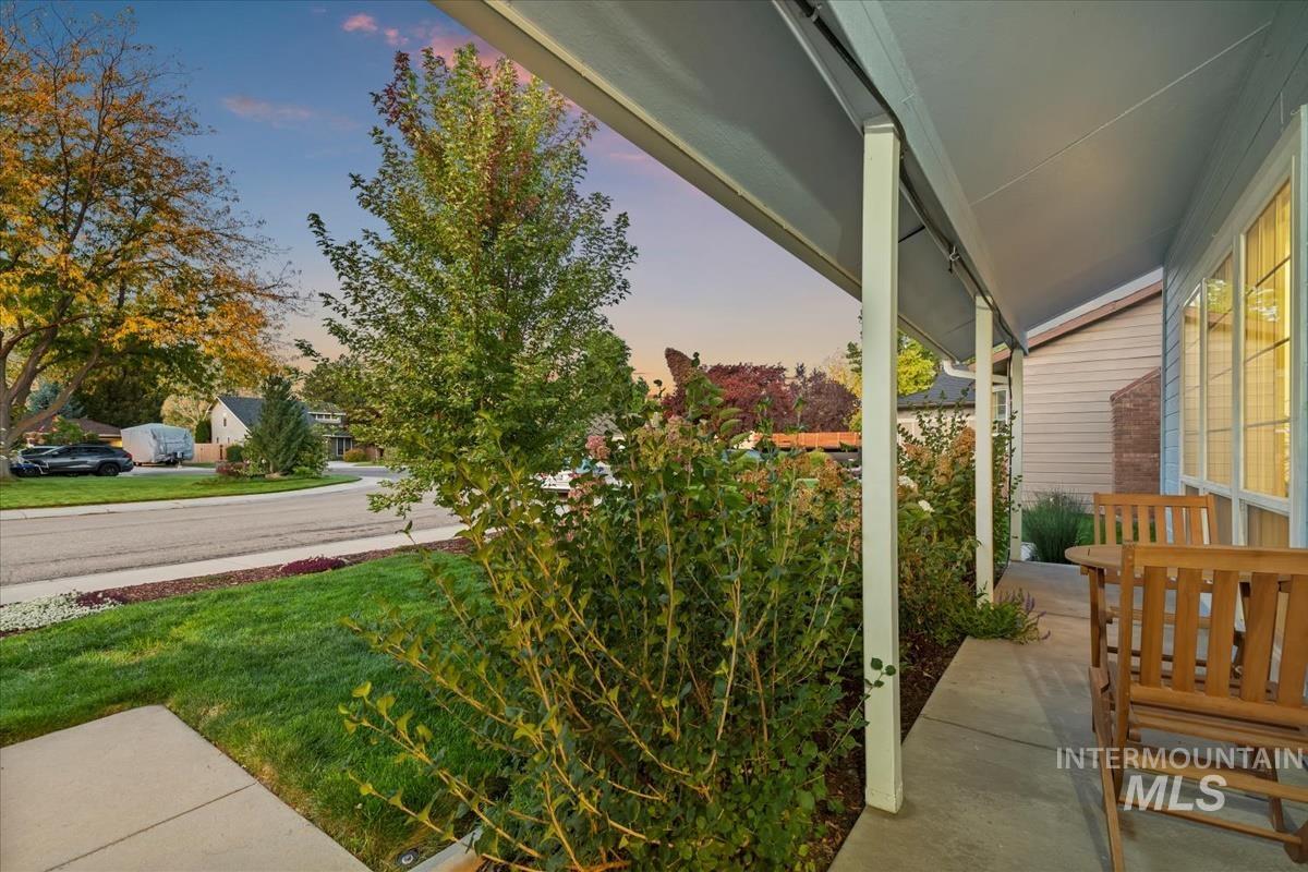 Patio terrace at dusk featuring covered porch and a lawn
