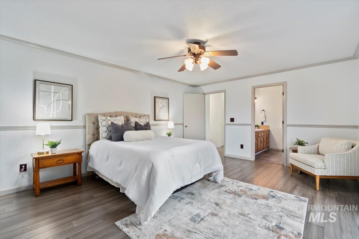 Bedroom with ornamental molding, wood finished floors, ensuite bathroom, and ceiling fan