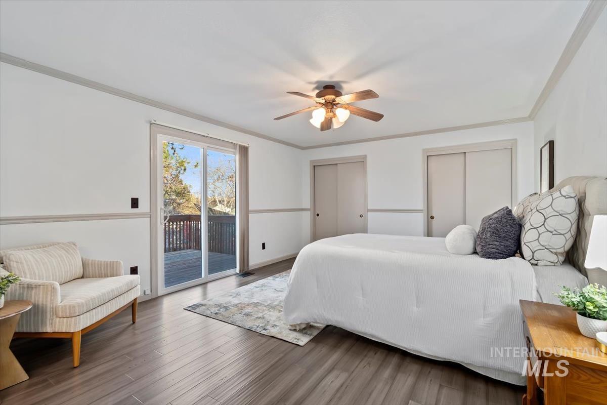 Bedroom with multiple closets, ornamental molding, access to exterior, wood finished floors, and ceiling fan