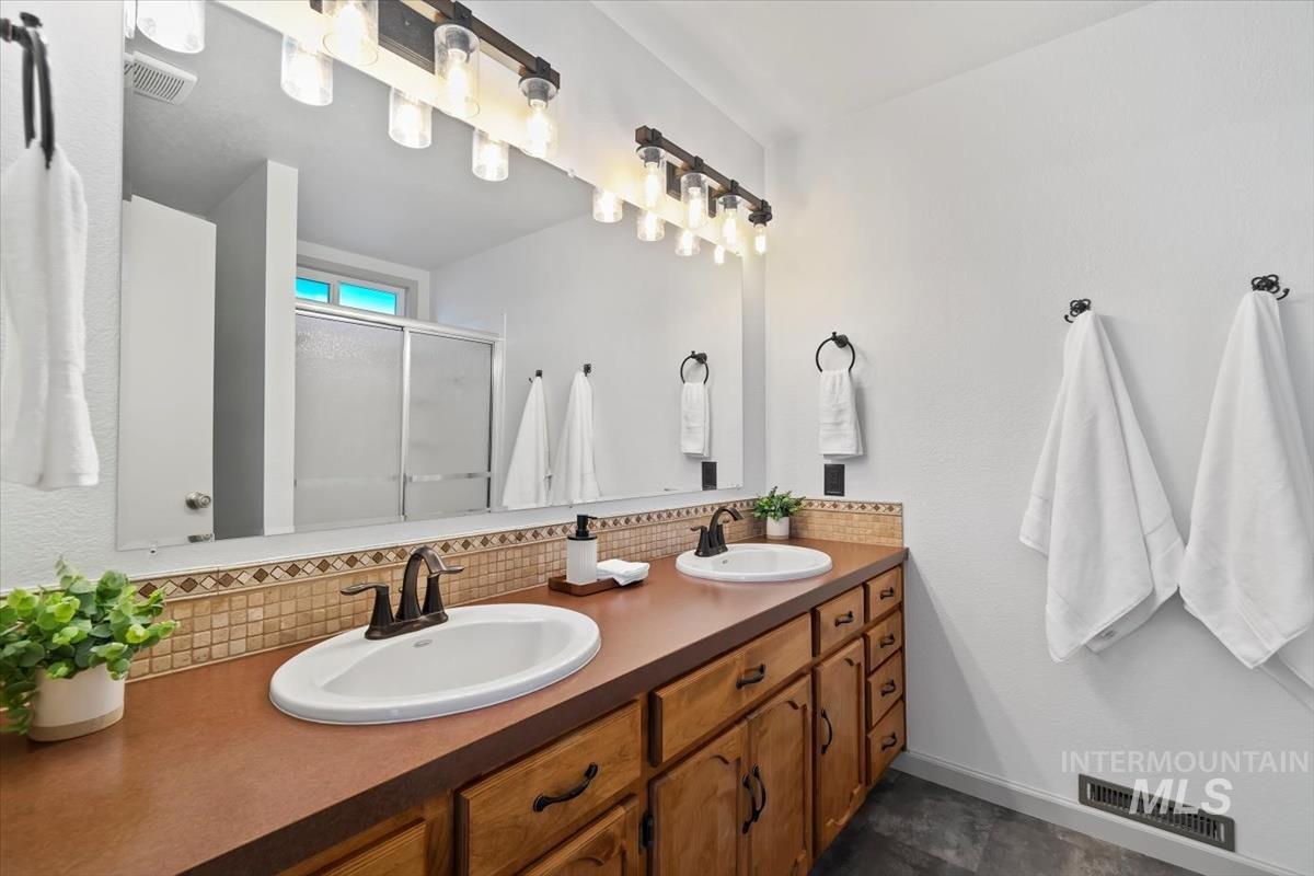 Full bathroom with a stall shower, double vanity, and decorative backsplash