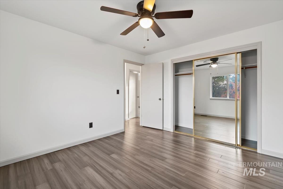 Unfurnished bedroom with ceiling fan, wood finished floors, and a closet