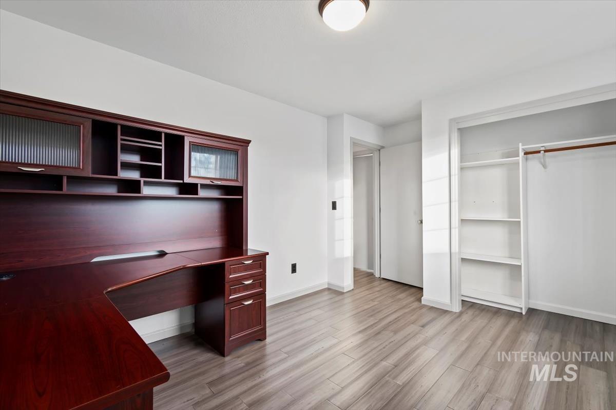Unfurnished office featuring light wood-style flooring and baseboards