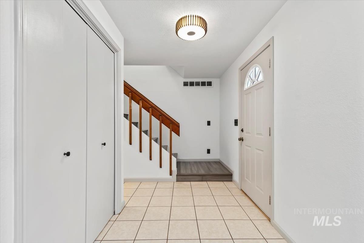 Entryway with light tile patterned floors and stairs