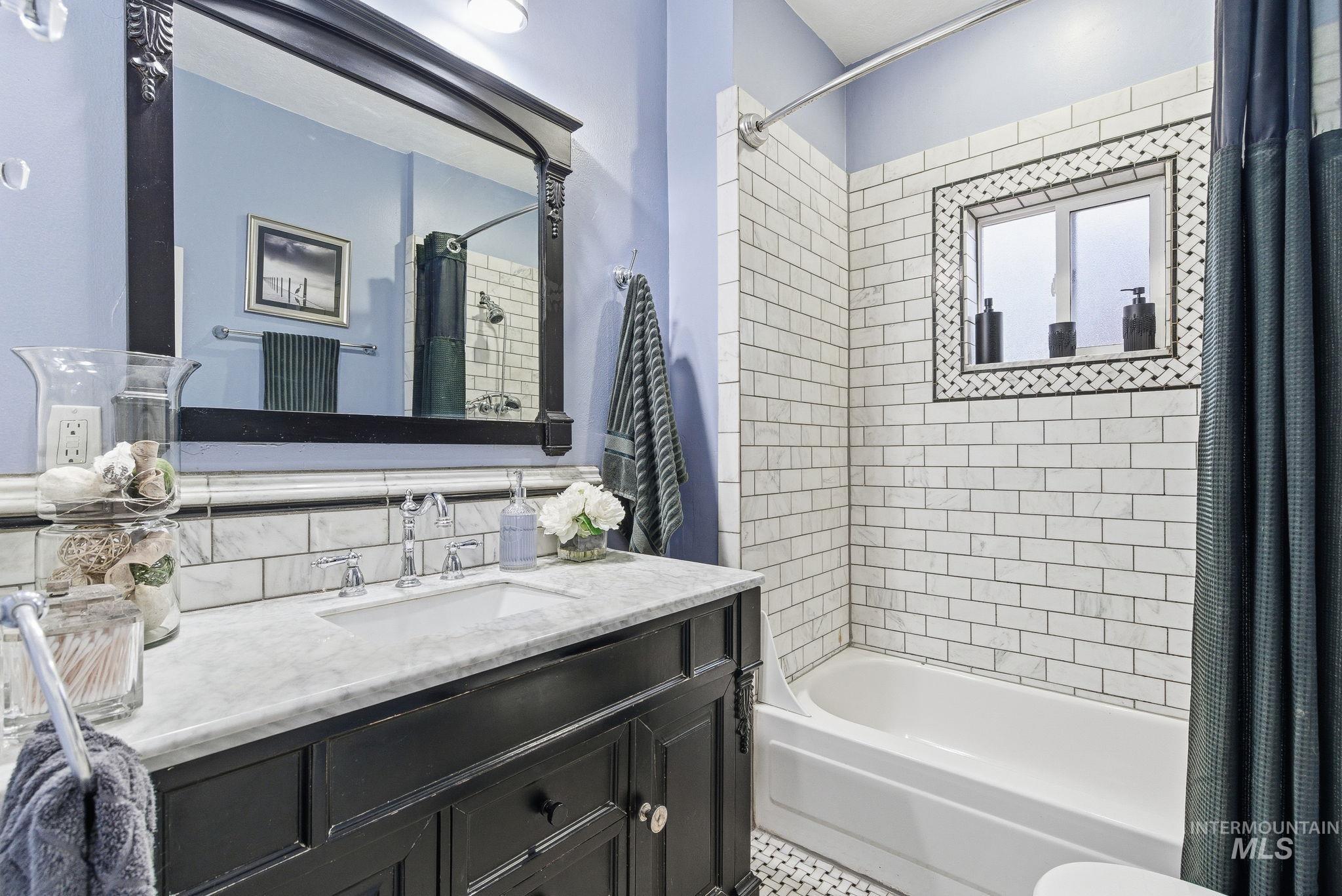 Full bathroom with vanity, shower / bath combo with shower curtain, and decorative backsplash