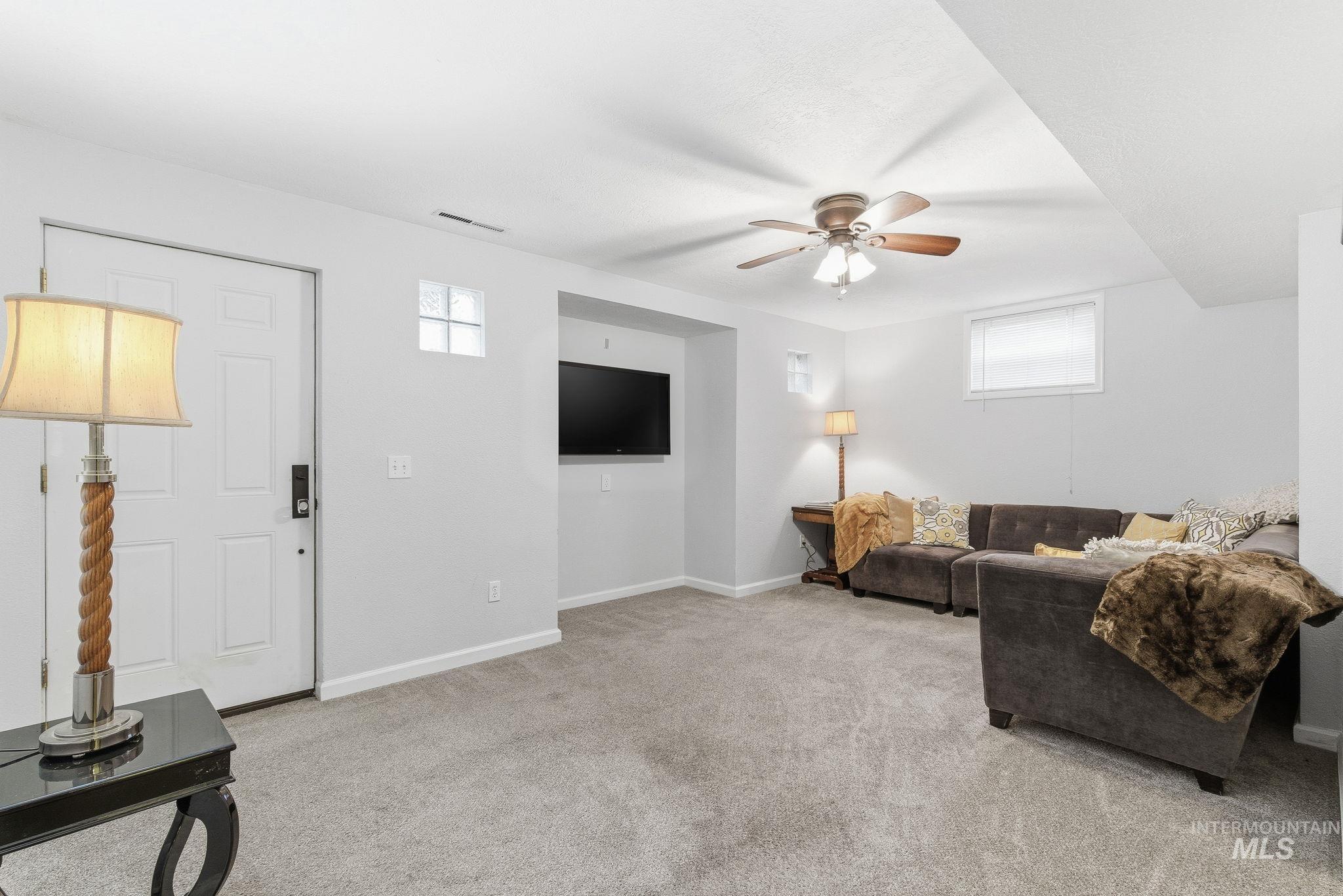 Living area featuring plenty of natural light, light carpet, and ceiling fan