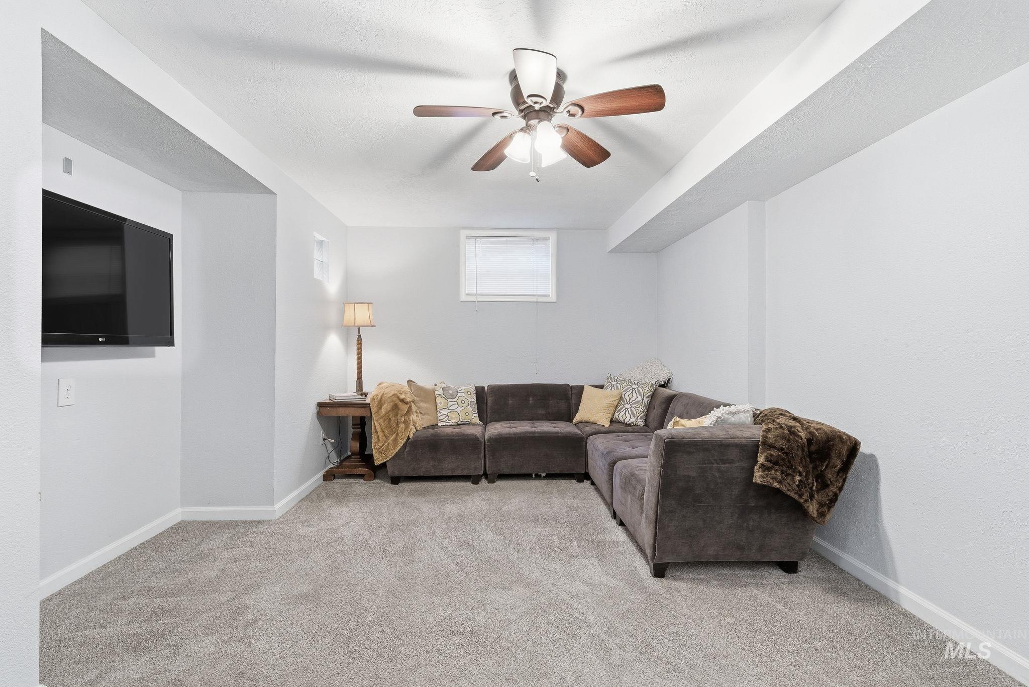 Living area featuring light colored carpet and ceiling fan